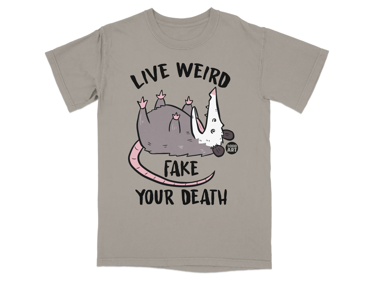 Gray opossum with text "LIVE WEIRD FAKE YOUR DEATH" on a taupe t-shirt.