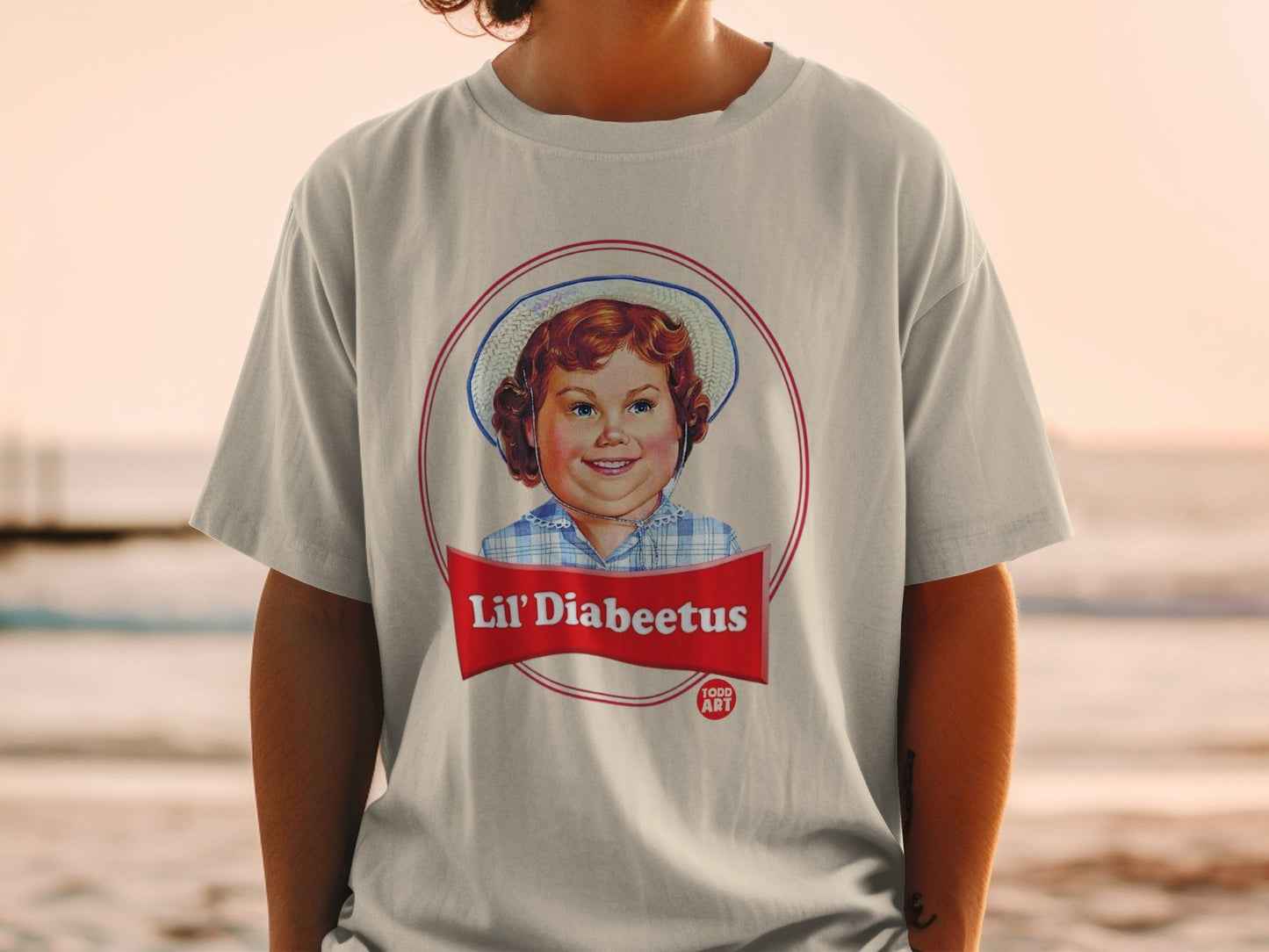 T-shirt with a circular logo featuring a smiling child and text "Lil' Diabeetus Food Art".