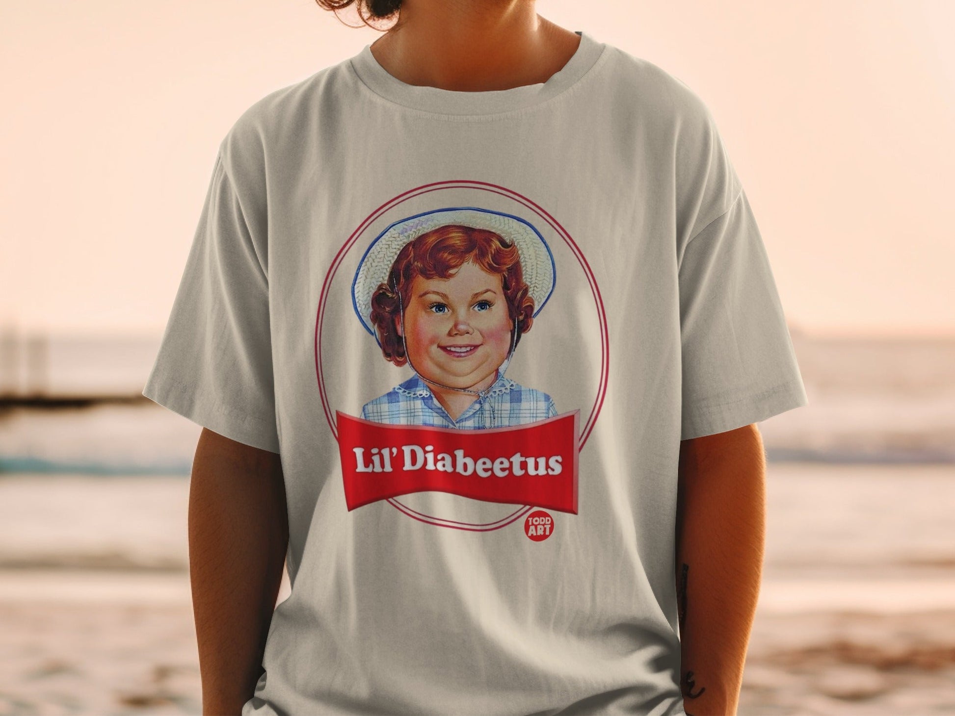 T-shirt with a circular logo featuring a smiling child and text "Lil' Diabeetus Food Art".