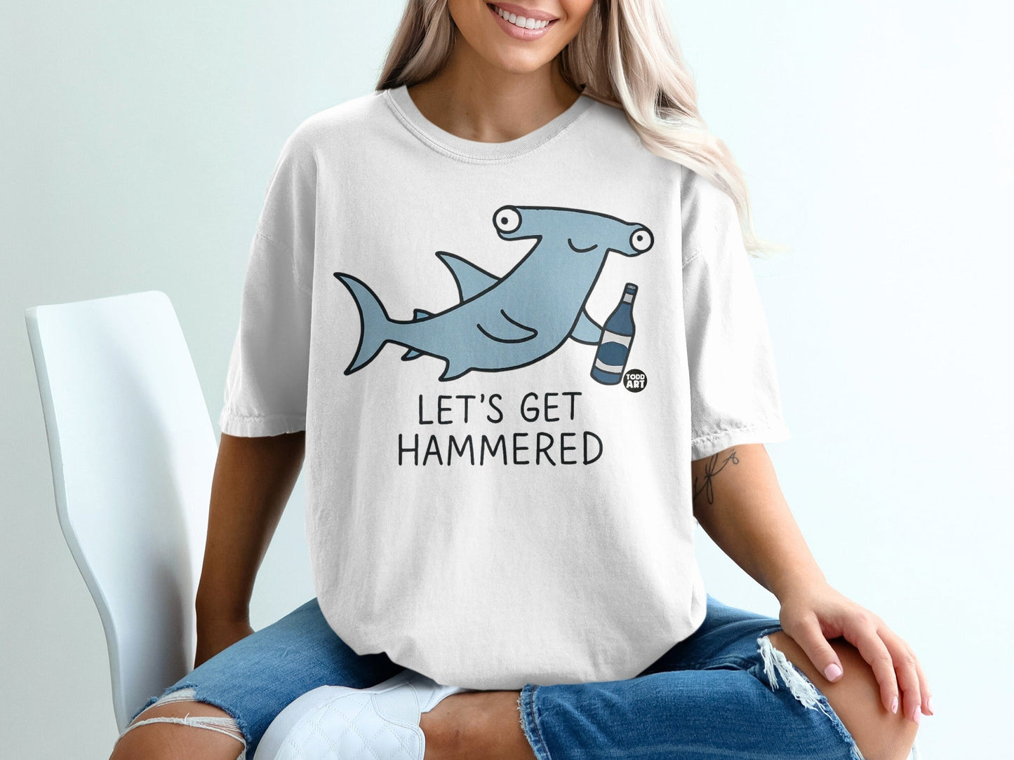 T-shirt with cartoon hammerhead shark holding a beer bottle, text "LET'S GET HAMMERED".
