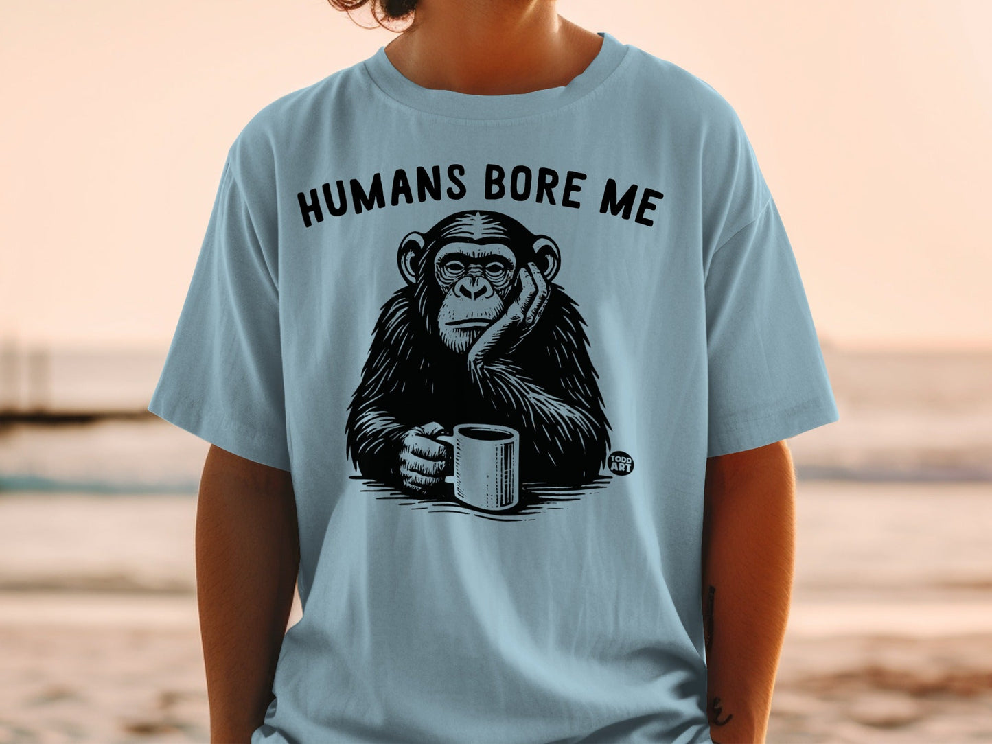 Light blue t-shirt with a chimpanzee holding a mug and text that says "HUMANS BORE ME".