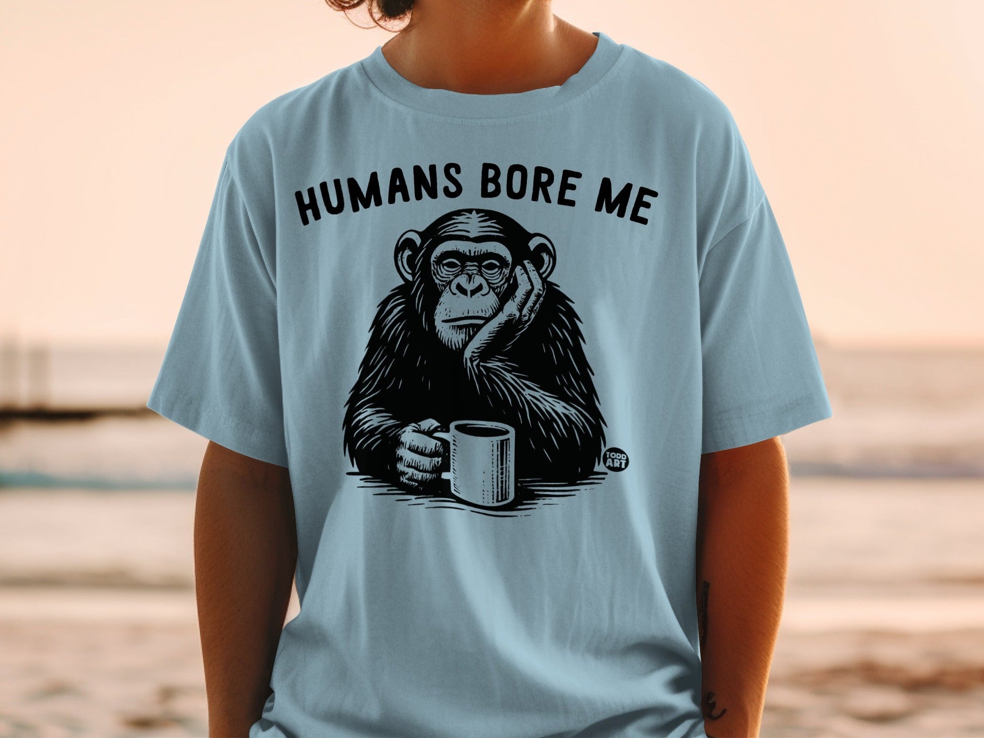 Light blue t-shirt with a chimpanzee holding a mug and text that says "HUMANS BORE ME".