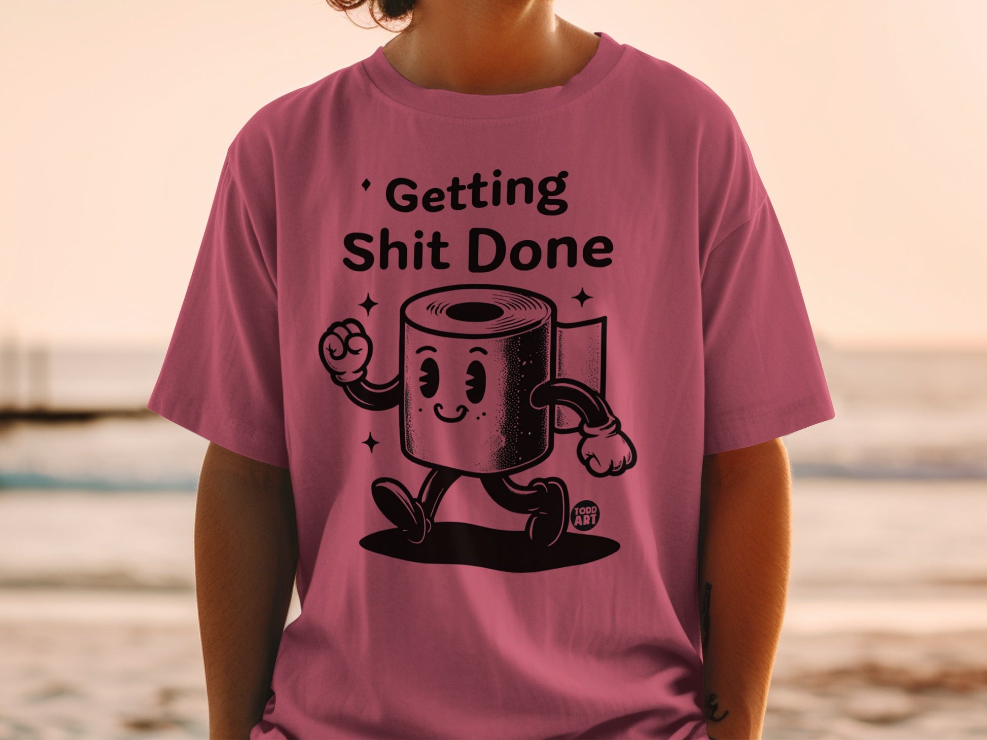 Pink t-shirt with cartoon toilet paper roll saying "Getting Shit Done".