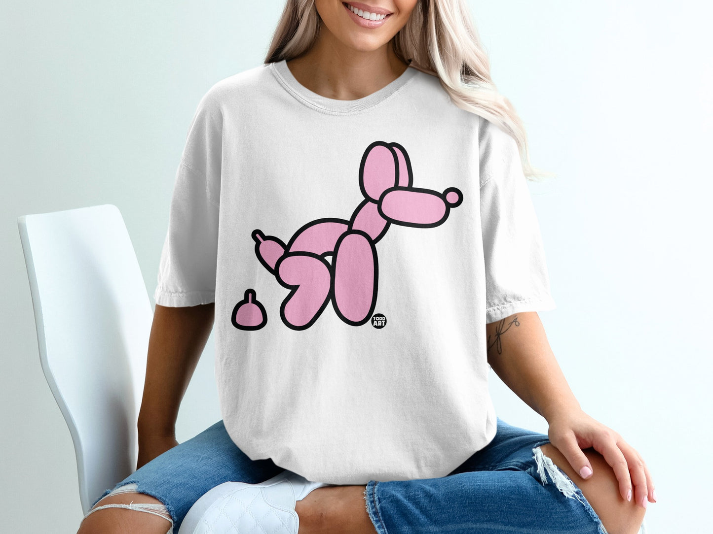 White t-shirt with pink balloon dog and poop graphic.