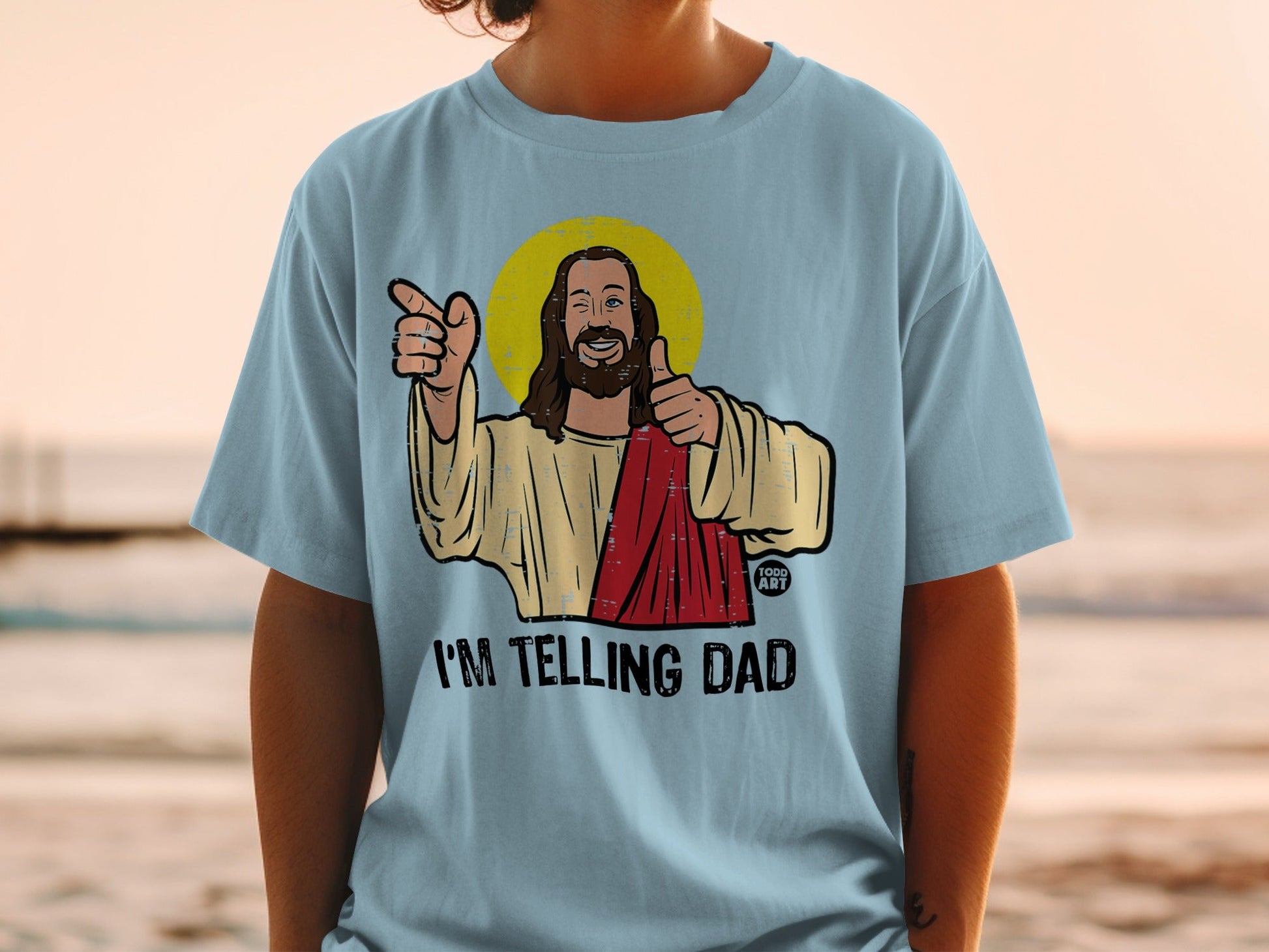 Light blue t-shirt with Jesus graphic saying "I'M TELLING DAD".