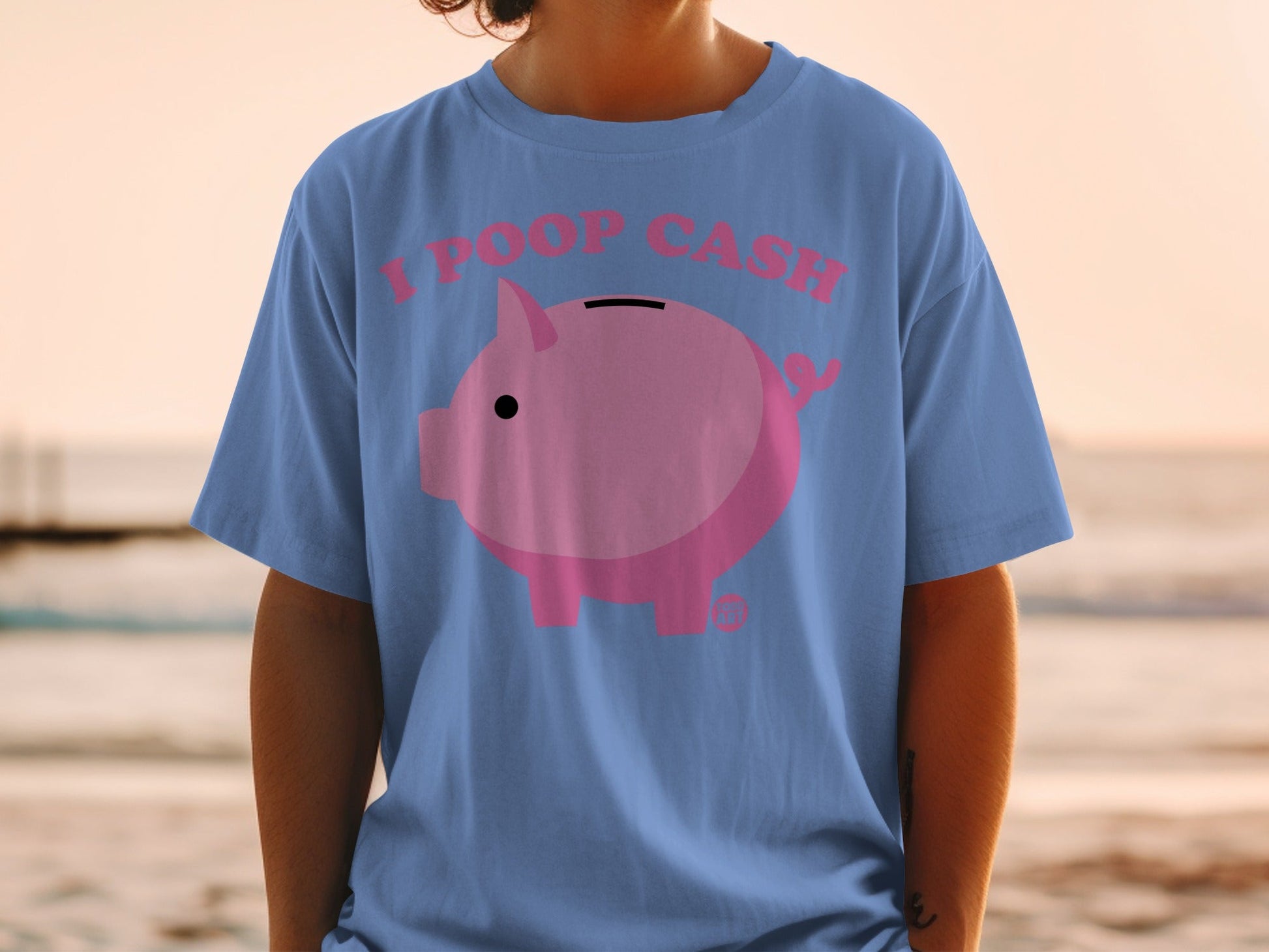 Pink piggy bank graphic with text "I POOP CASH" on blue t-shirt.