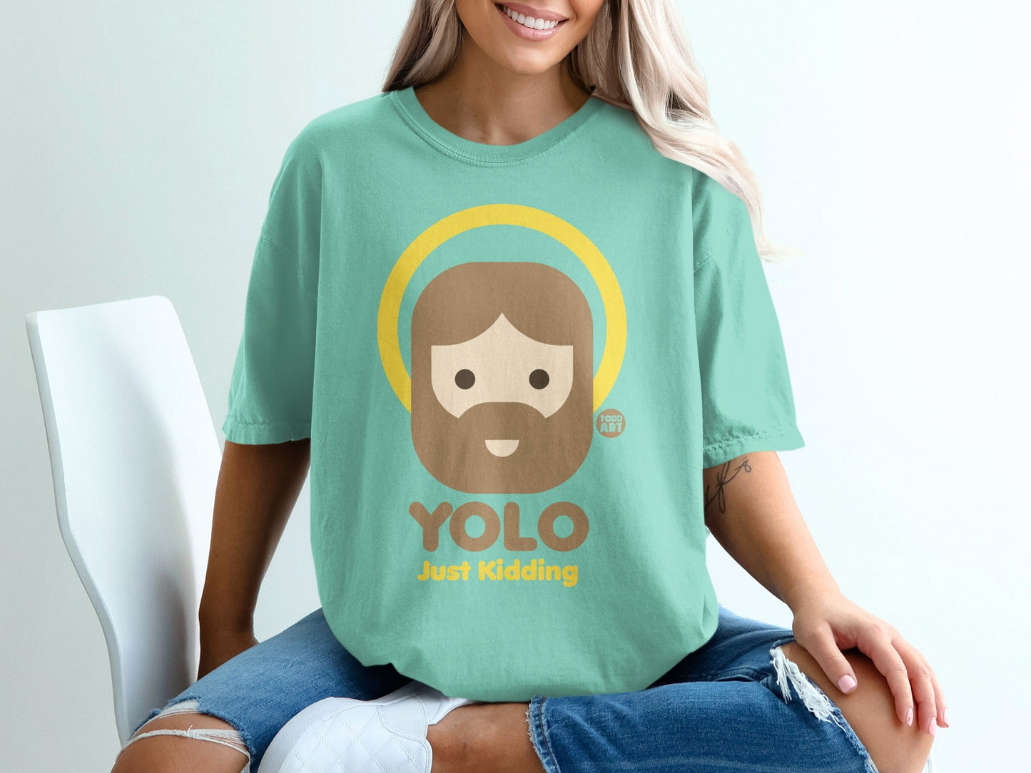 Teal t-shirt with "YOLO Just Kidding" and cartoon Jesus graphic.