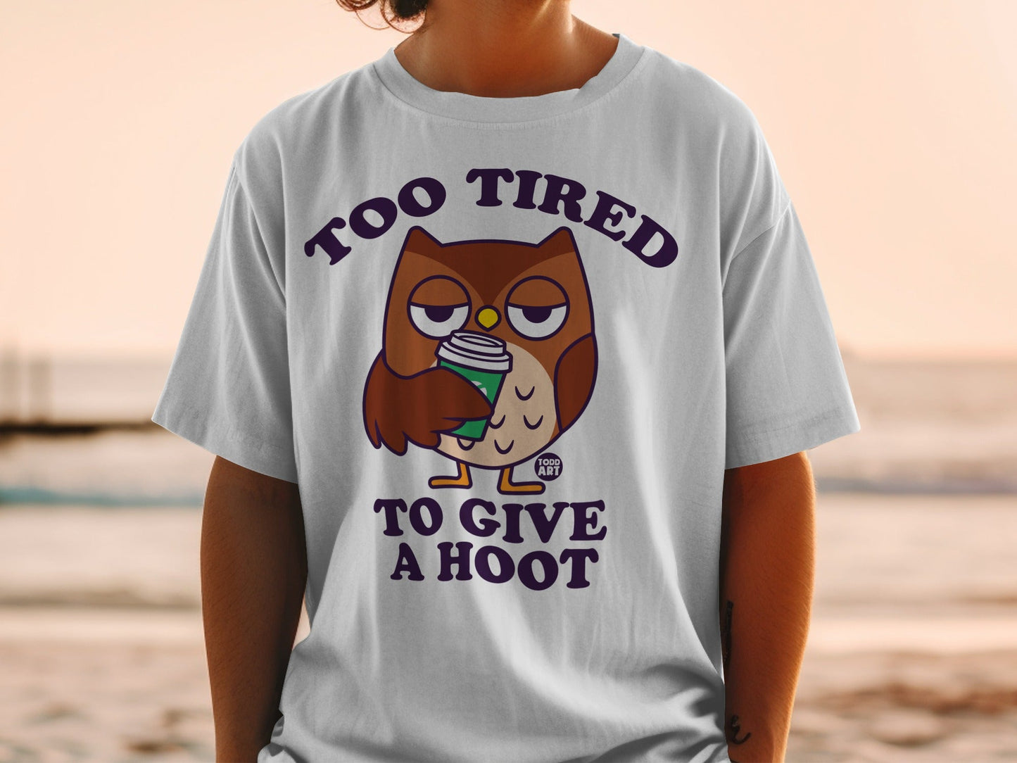 T-shirt with a tired owl holding a coffee cup and the text "Too Tired To Give A Hoot".