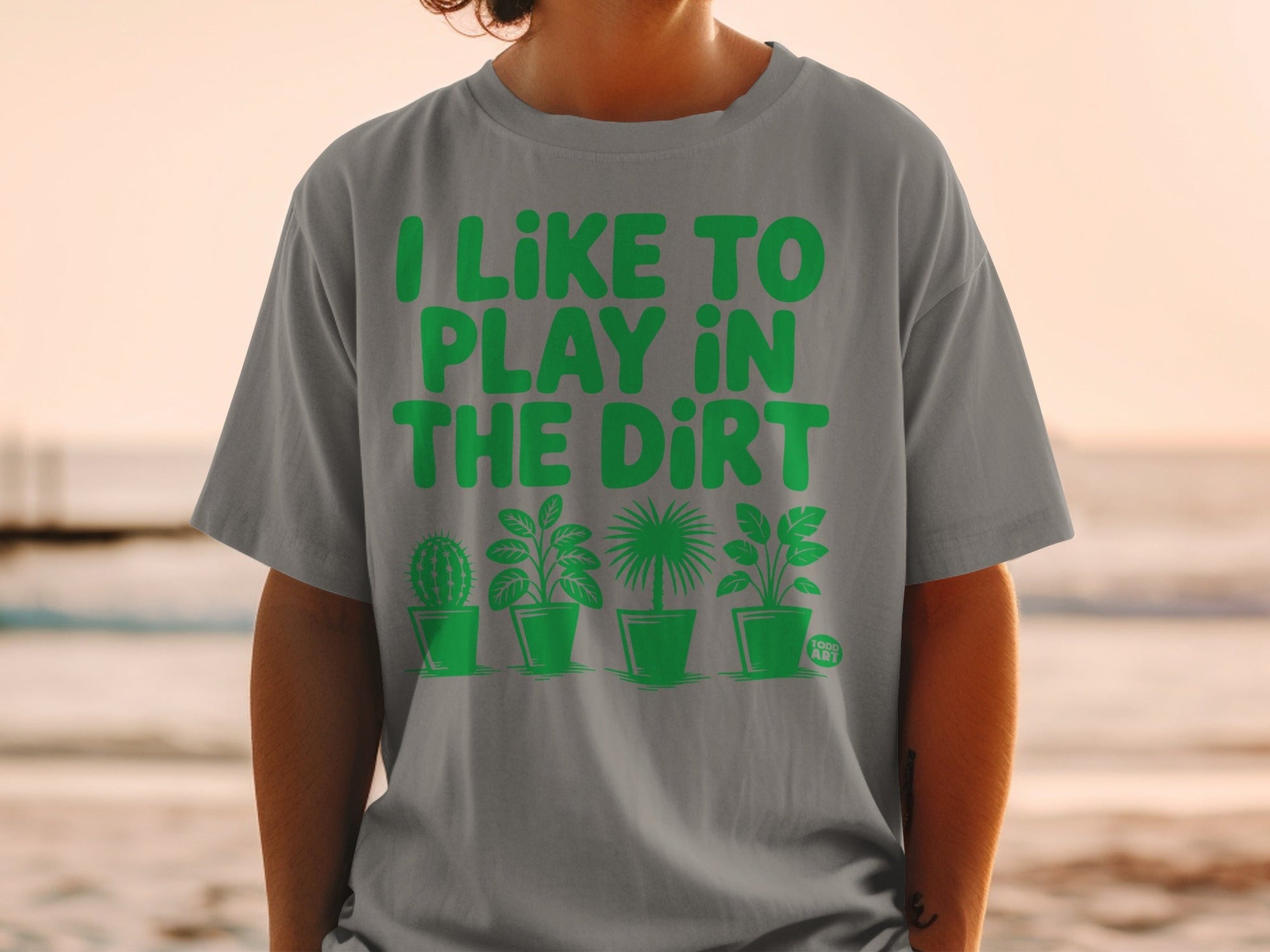 Grey t-shirt with "I LIKE TO PLAY IN THE DIRT" and plant graphics.