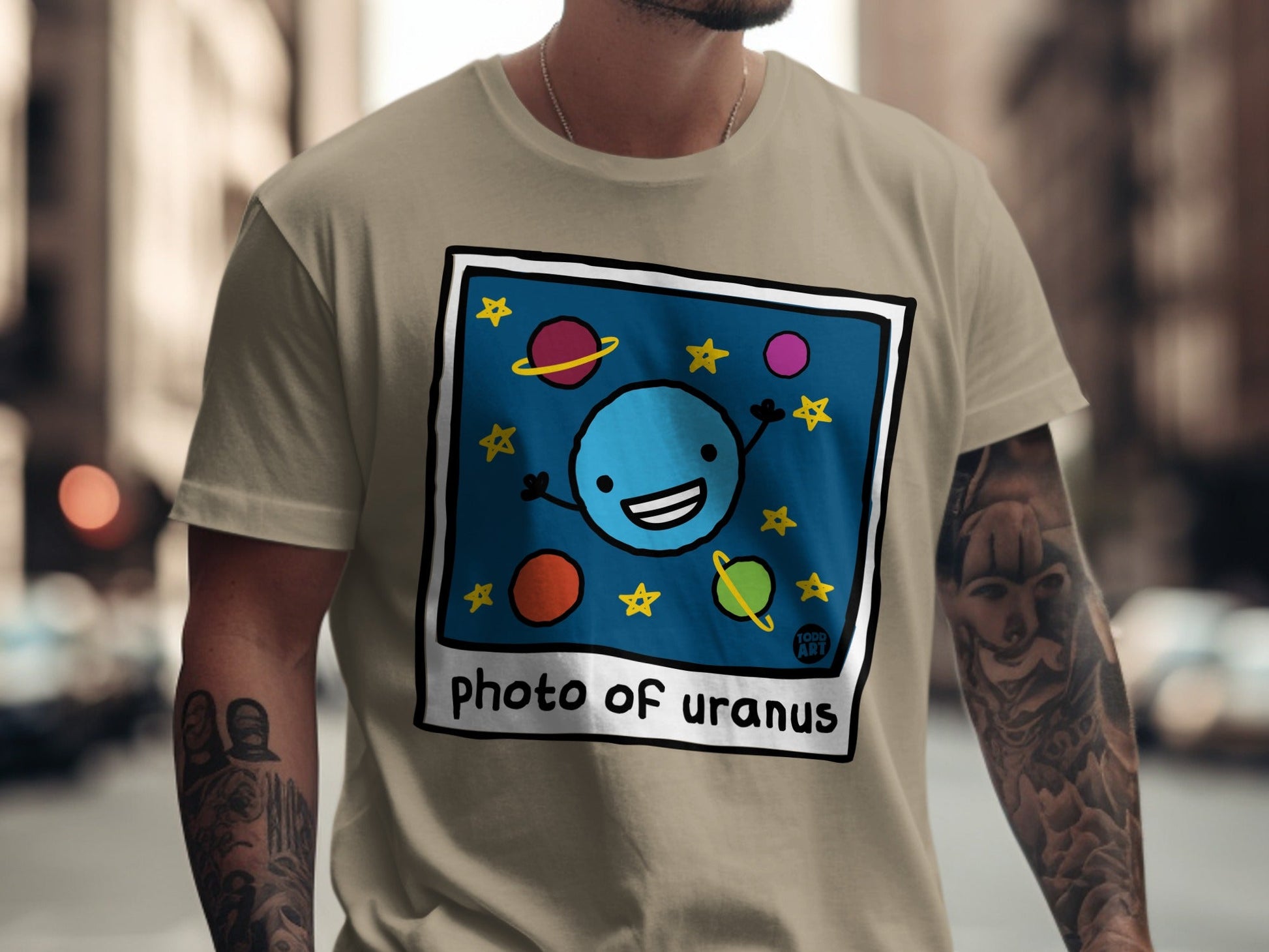 Cartoon blue planet with stars and smiling face on tan t-shirt.