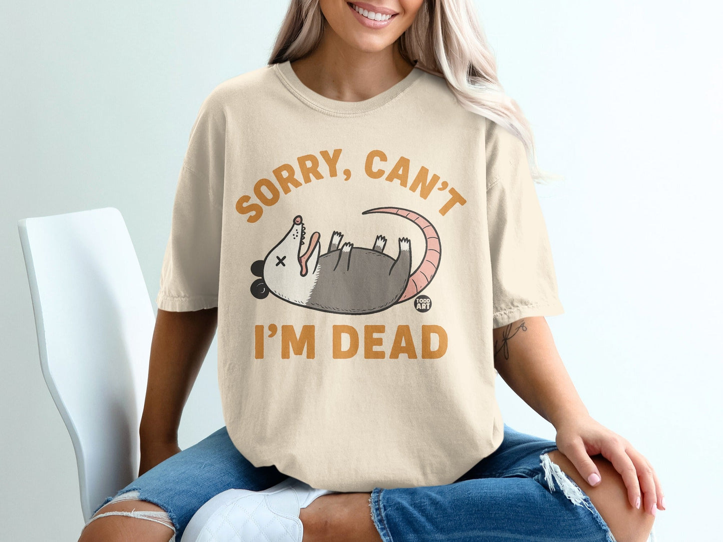 Cream t-shirt with "Sorry, can't I'm dead" graphic of a possum.