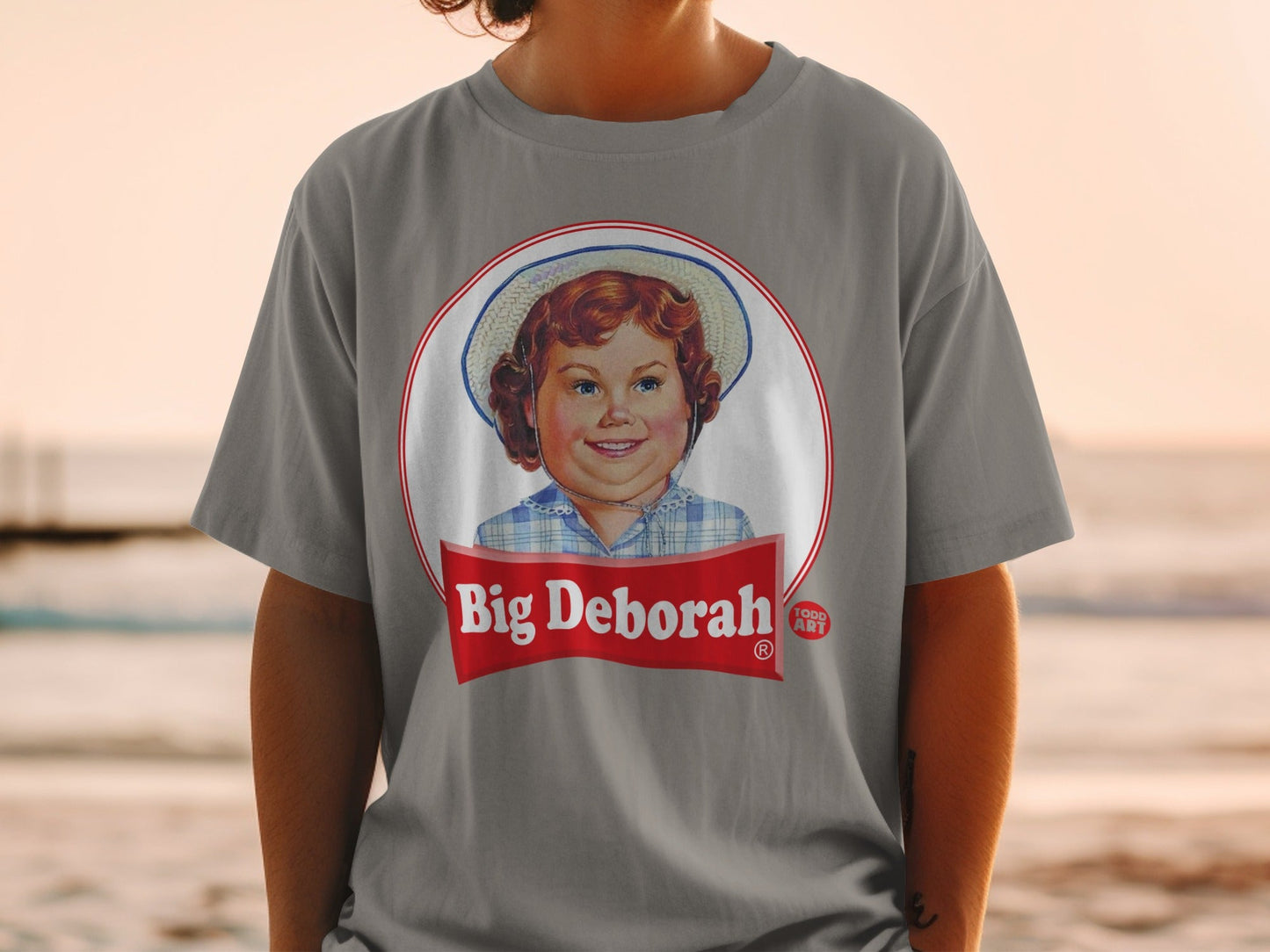 Grey t-shirt with a circular Big Deborah logo featuring a young girl.