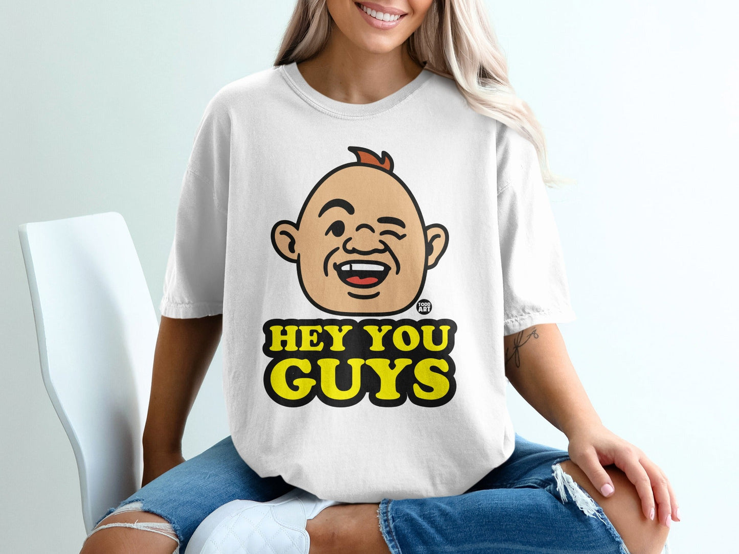 White t-shirt with cartoon character winking and text "HEY YOU GUYS".