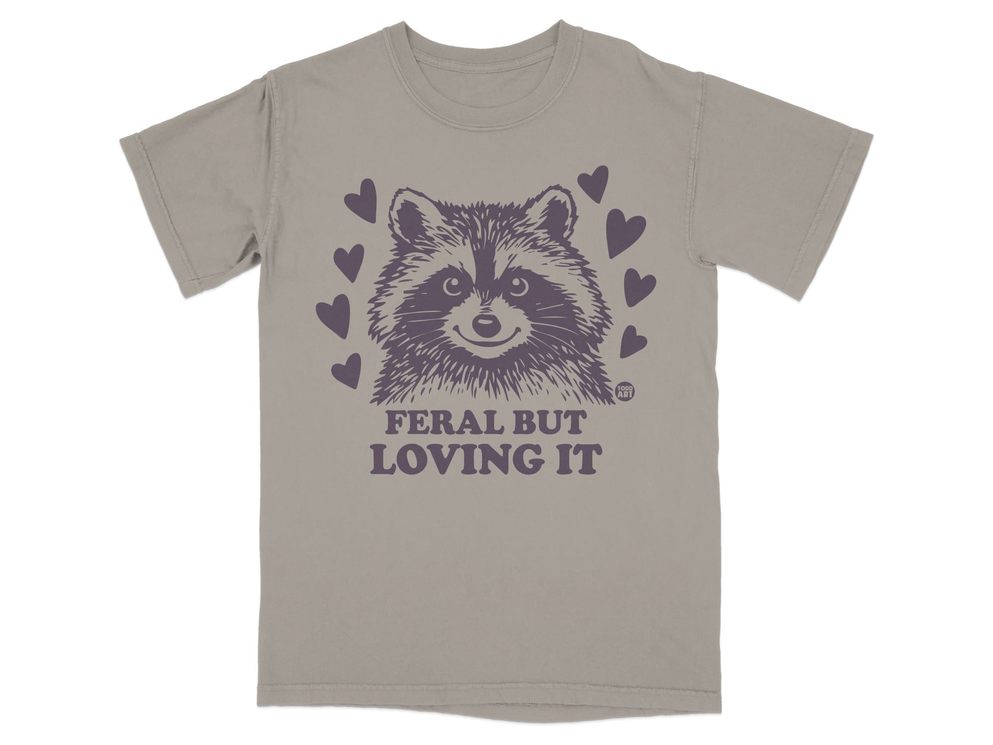 T-shirt with a raccoon graphic and text "FERAL BUT LOVING IT" surrounded by hearts.