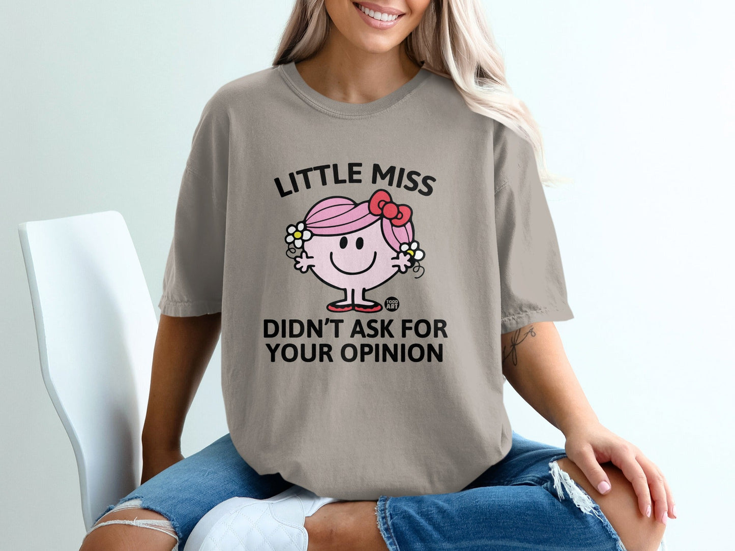 Little Miss character on beige t-shirt with text "DIDN'T ASK FOR YOUR OPINION".