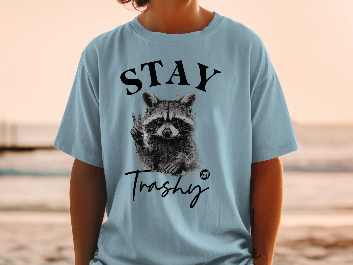 Light blue t-shirt with raccoon graphic and "STAY Trashy" text.