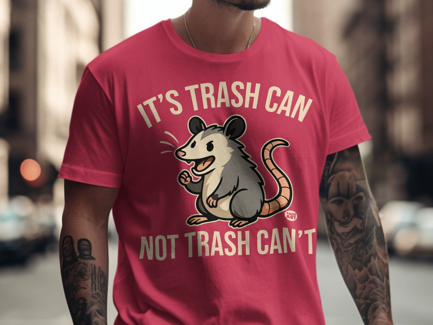 Pink t-shirt with cartoon opossum and text "IT'S TRASH CAN NOT TRASH CAN'T".