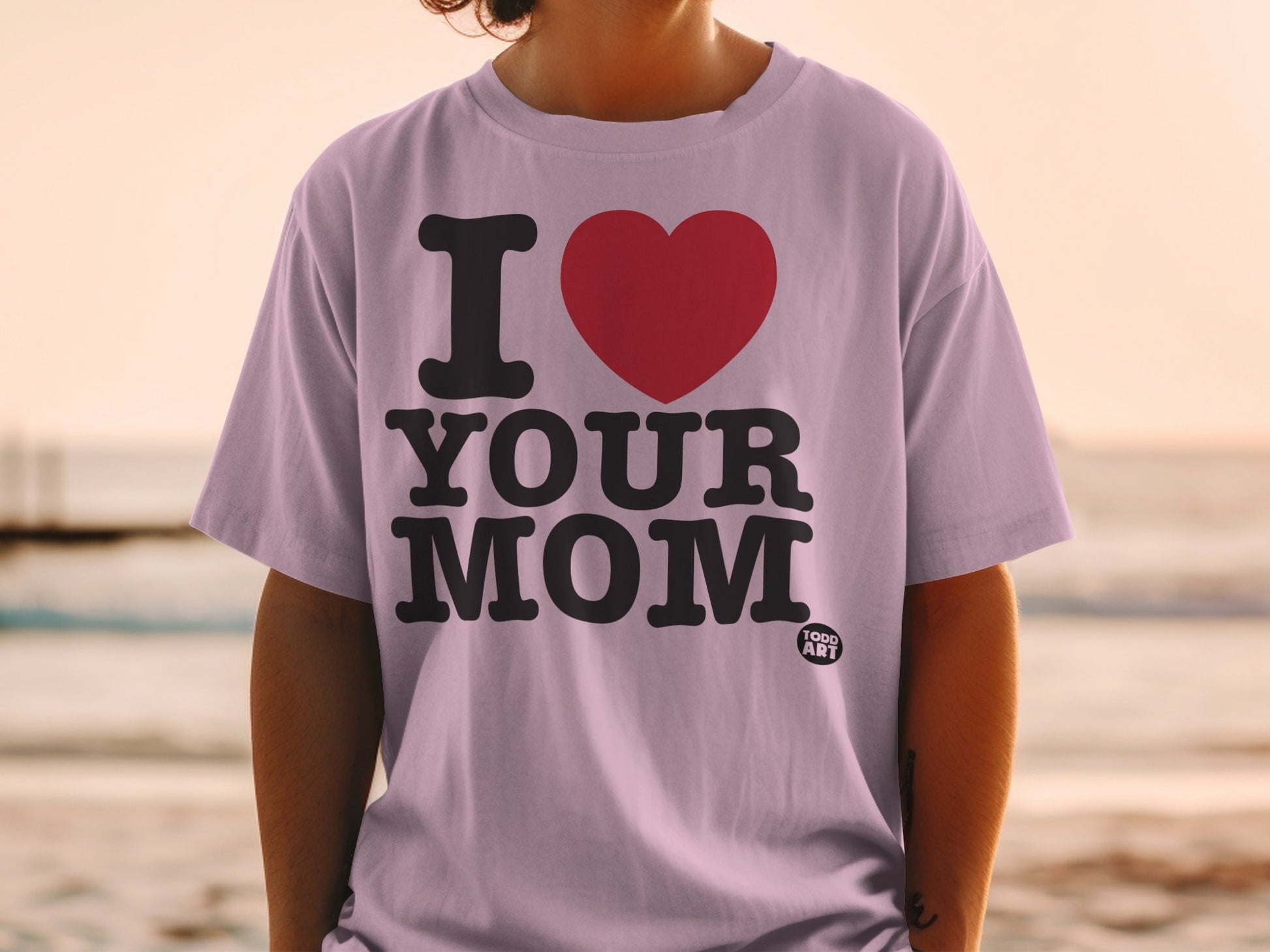 Lilac t-shirt with bold black text "I ‚ù§Ô∏è YOUR MOM" and a small "FOOD ART" logo.
