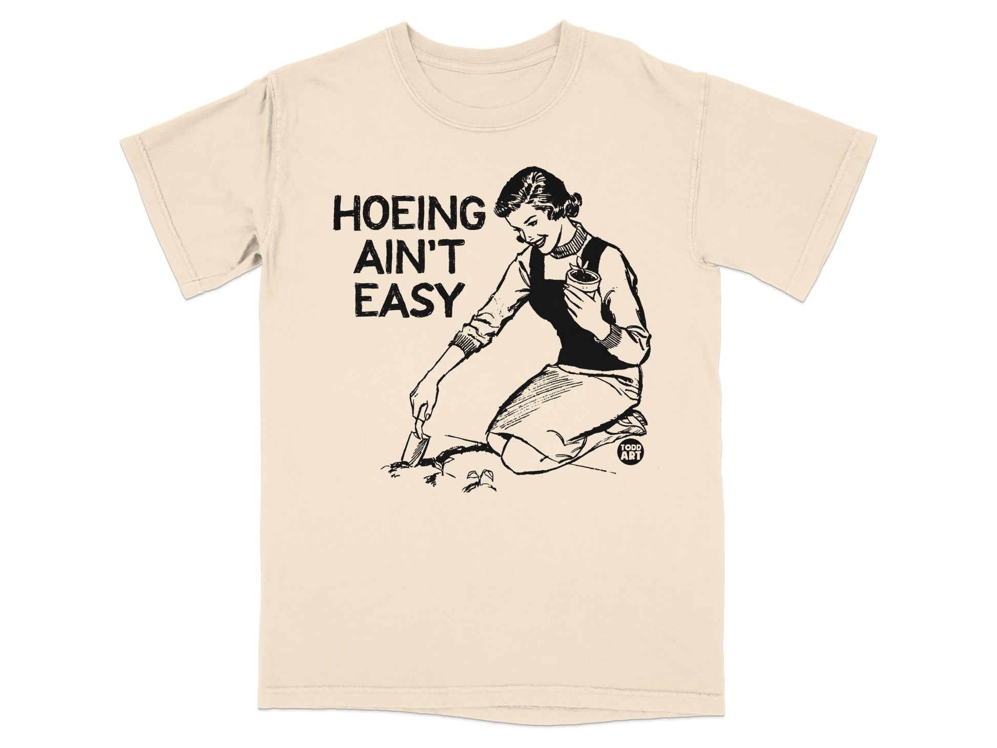 Woman gardening with text "Hoeing Ain't Easy" on a cream t-shirt.