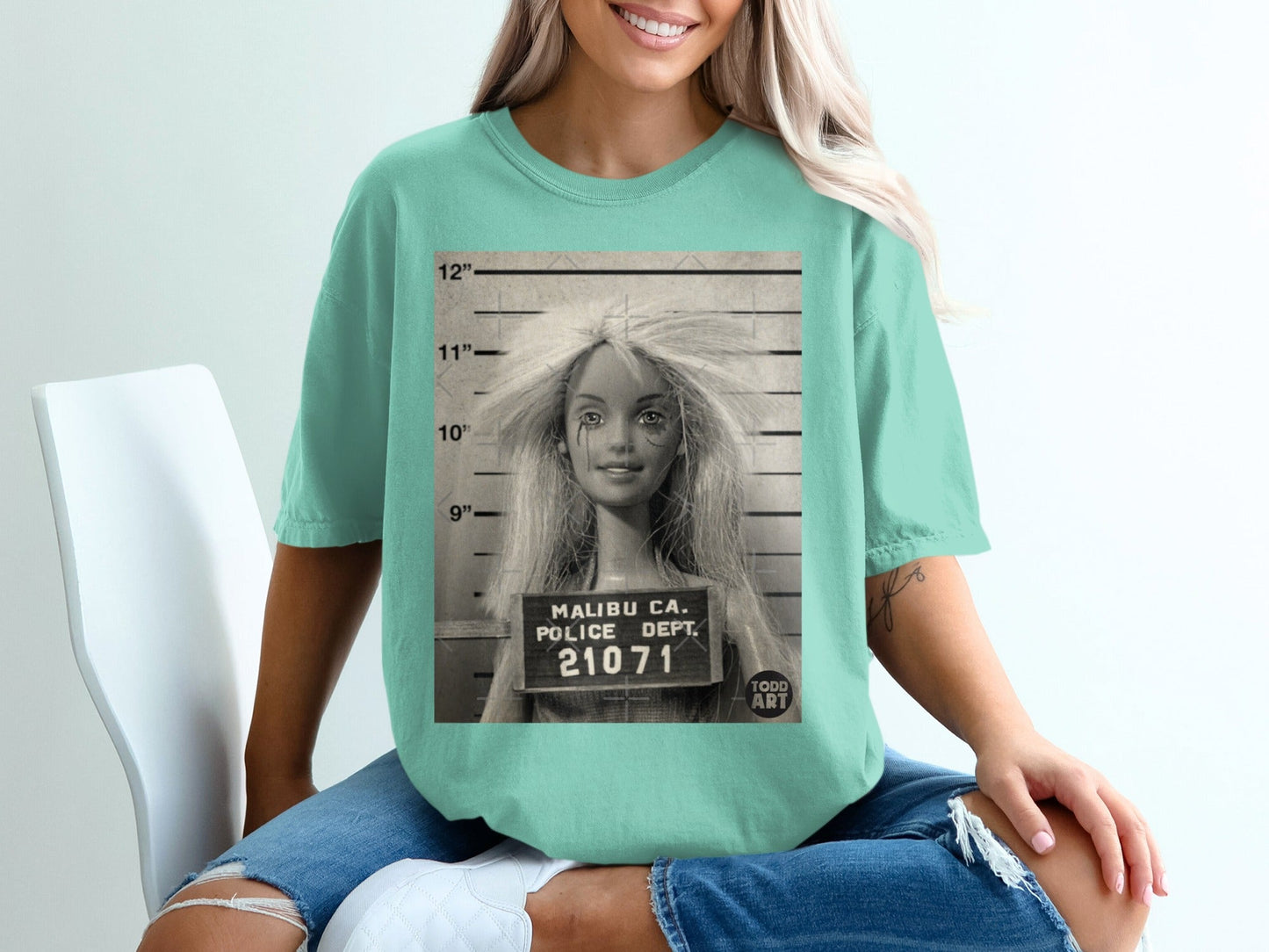 Mugshot of a woman with blond hair wearing a t-shirt that says "Malibu Ca. Police Dept."
