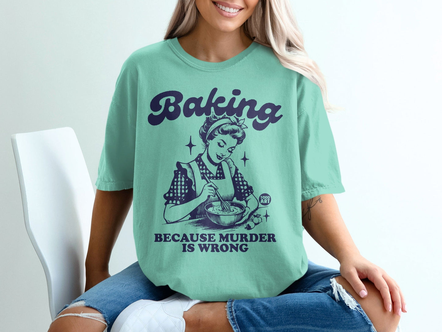 Mint green t-shirt with "Baking because murder is wrong" and retro illustration.