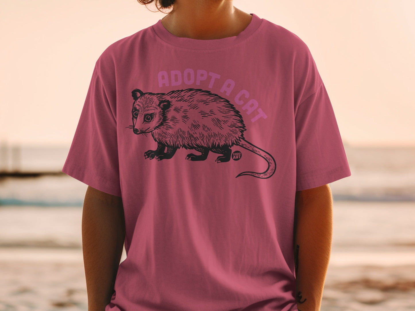 T-shirt with possum illustration and "Adopt a Cat" text.