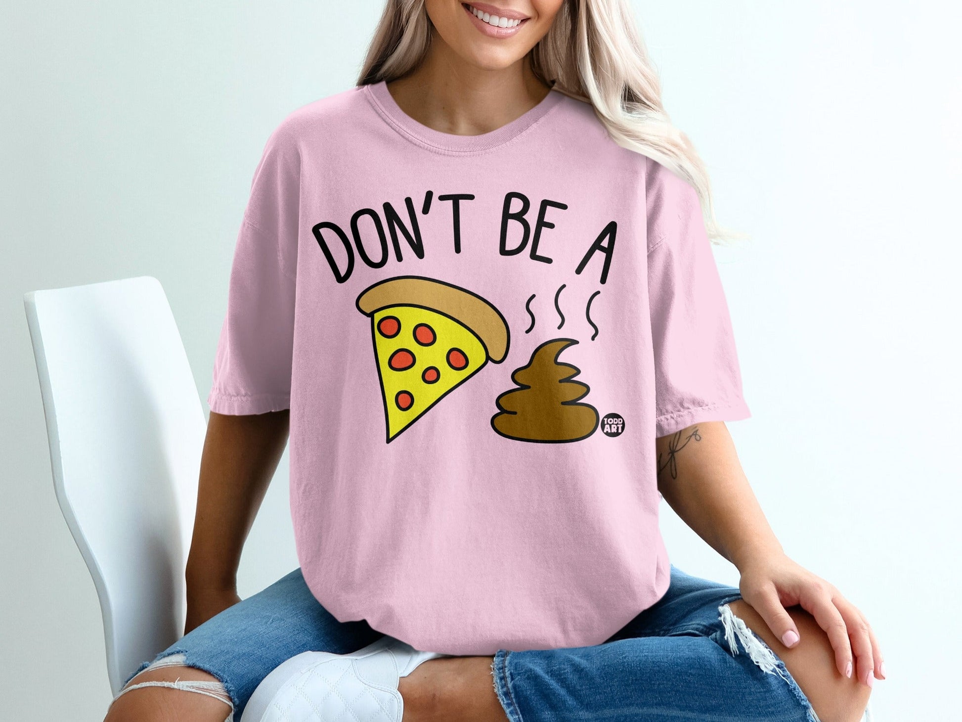 Pink t-shirt with cartoon pizza slice and brown poop emoji with text.