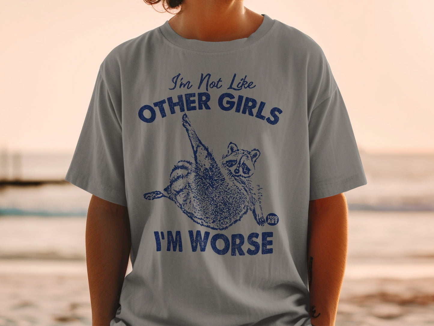 Gray t-shirt with blue graphic of raccoon and text "I'm Not Like Other Girls I'm Worse."