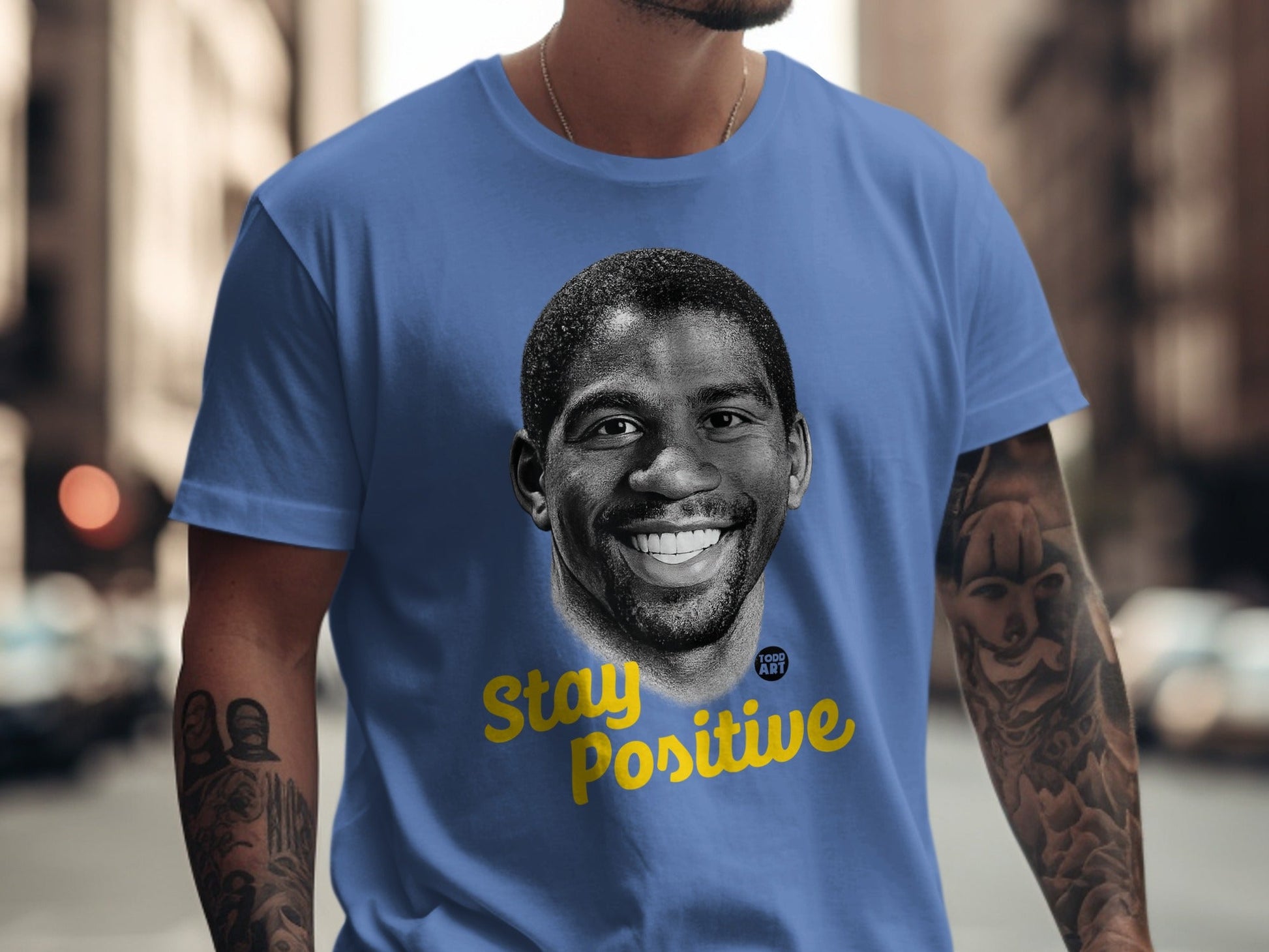 Blue t-shirt with a portrait of Magic Johnson and yellow "Stay Positive" text.