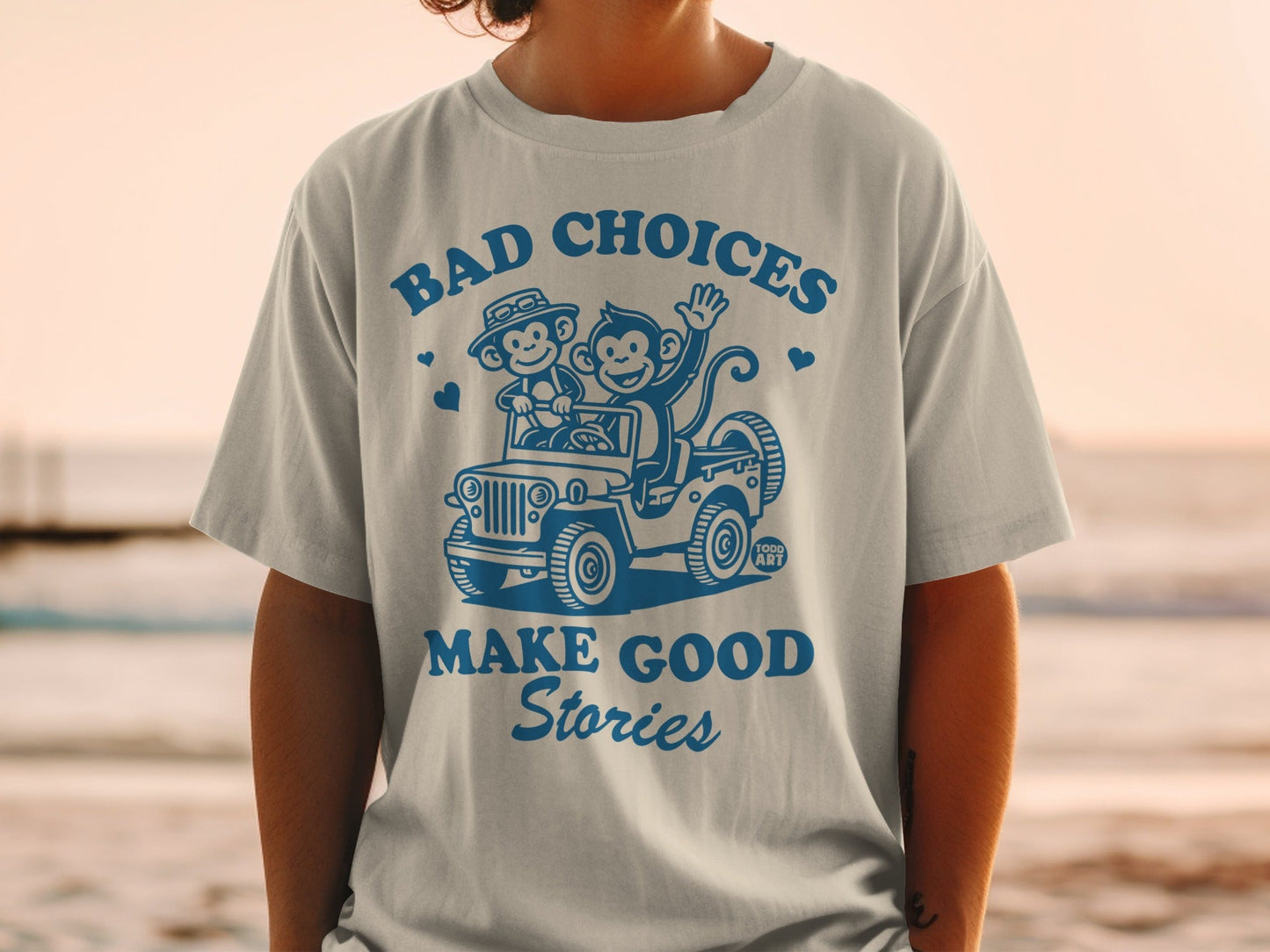 T-shirt with graphic of two monkeys driving a jeep with text "BAD CHOICES MAKE GOOD STORIES".