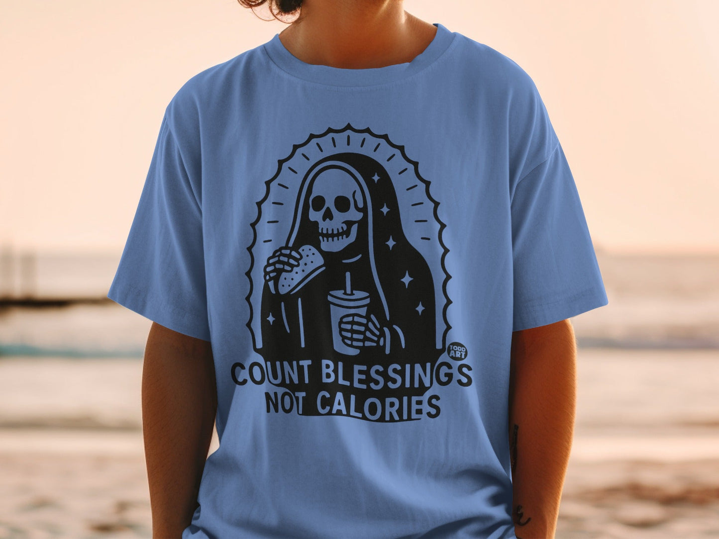 Skeleton wearing a robe, holding a burger and drink, text reads "COUNT BLESSINGS NOT CALORIES".