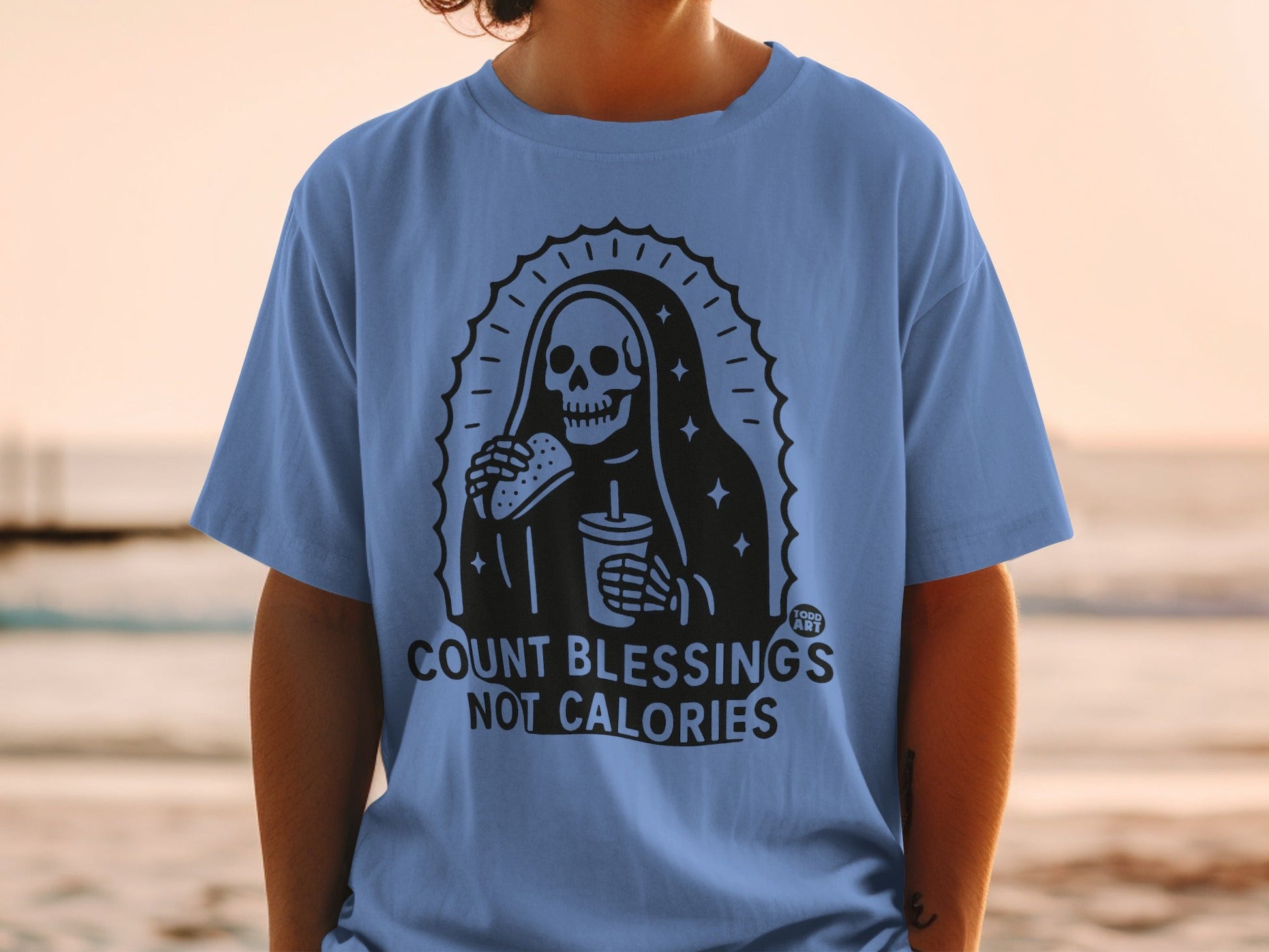 Skeleton wearing a robe, holding a burger and drink, text reads "COUNT BLESSINGS NOT CALORIES".