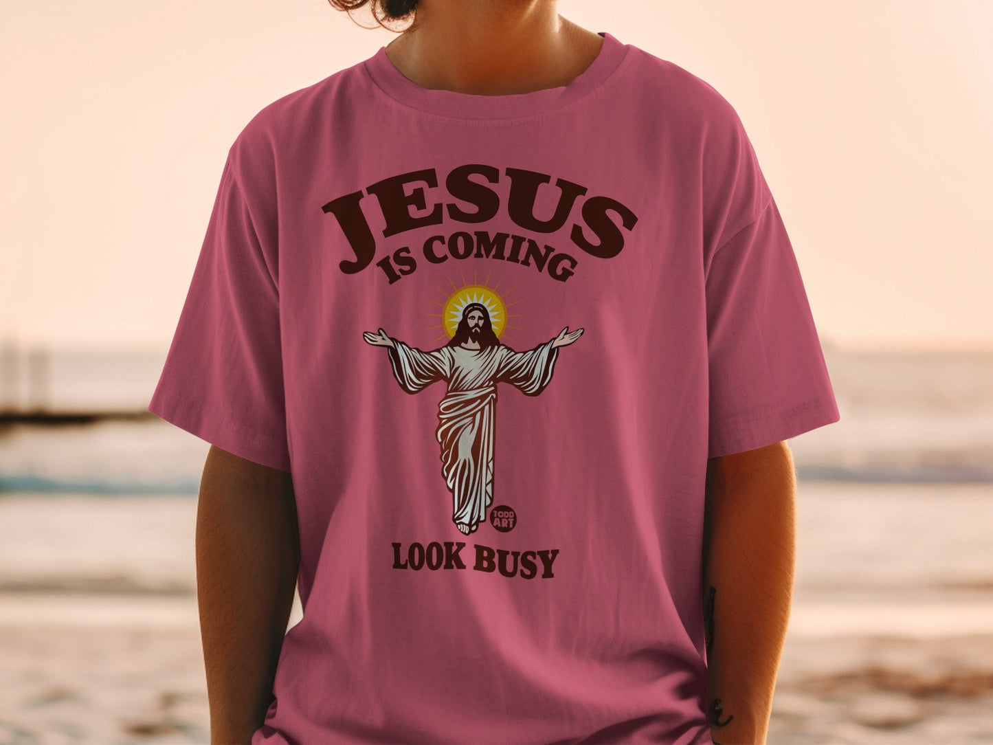 Pink t-shirt with Jesus illustration and "Jesus is coming look busy" text.