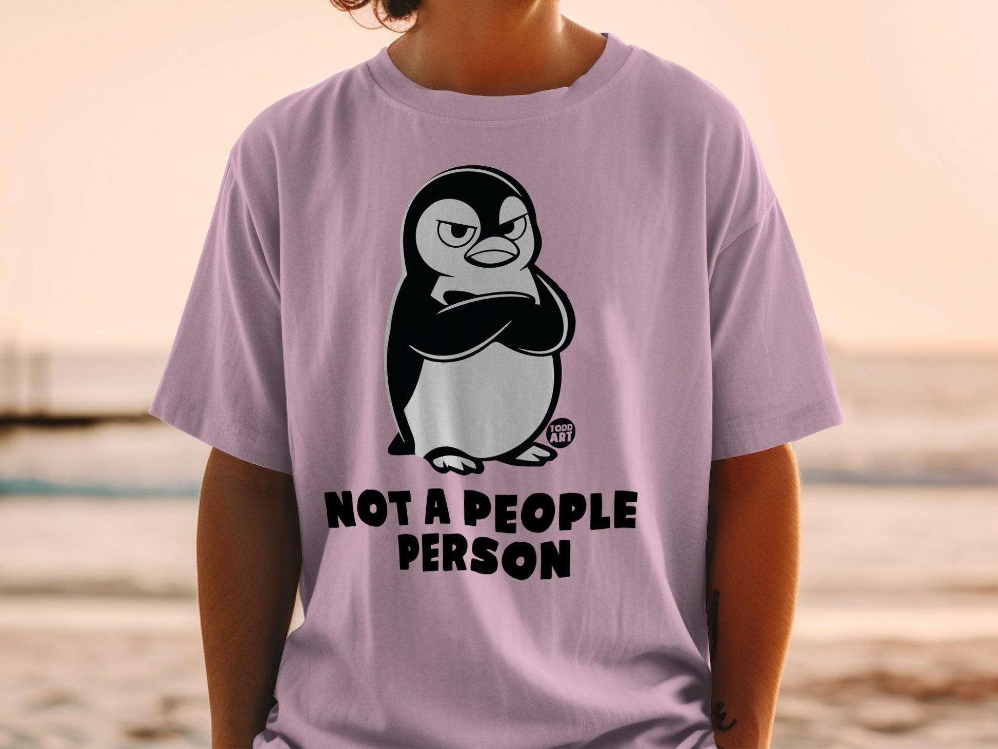 Pink t-shirt with grumpy penguin graphic and "Not a people person" text.