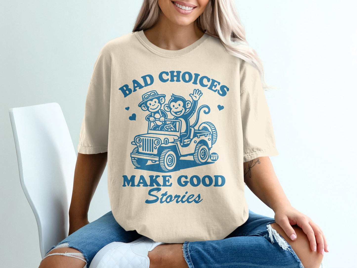 Cream t-shirt with "Bad Choices Make Good Stories" and cartoon monkeys in a jeep.
