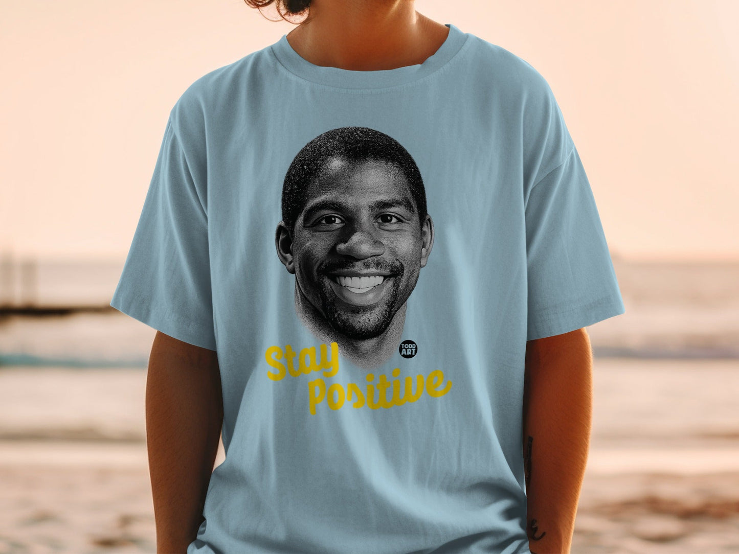 Light blue t-shirt with portrait of Magic Johnson and "Stay Positive" text.