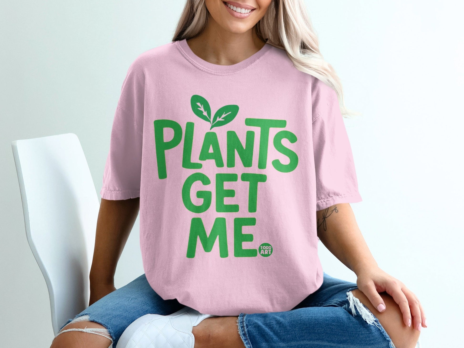 Pink t-shirt with green text that reads "PLANTS GET ME" and two green leaves.