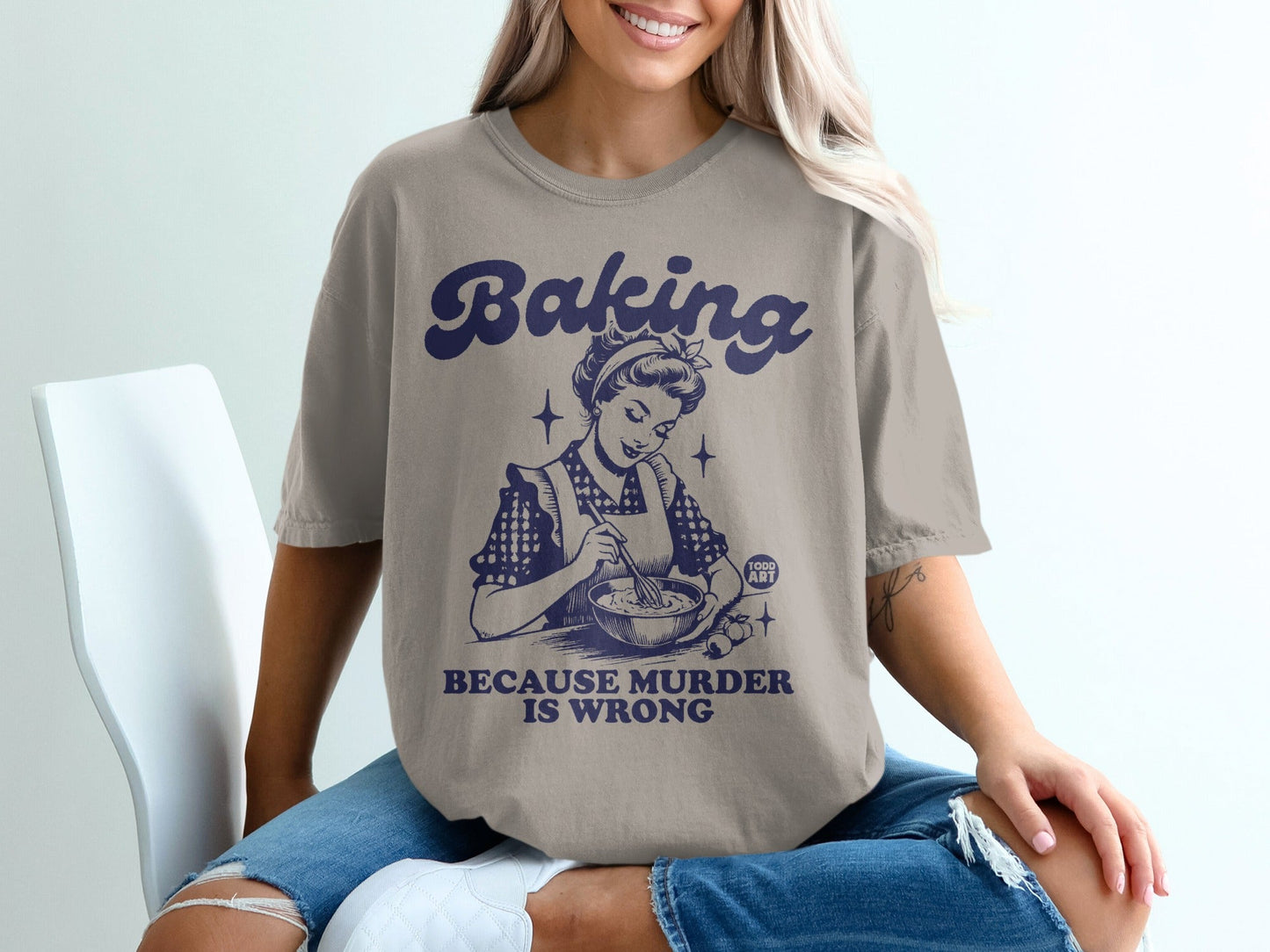 Woman wearing a t-shirt with "Baking Because Murder is Wrong" text and a vintage chef illustration.