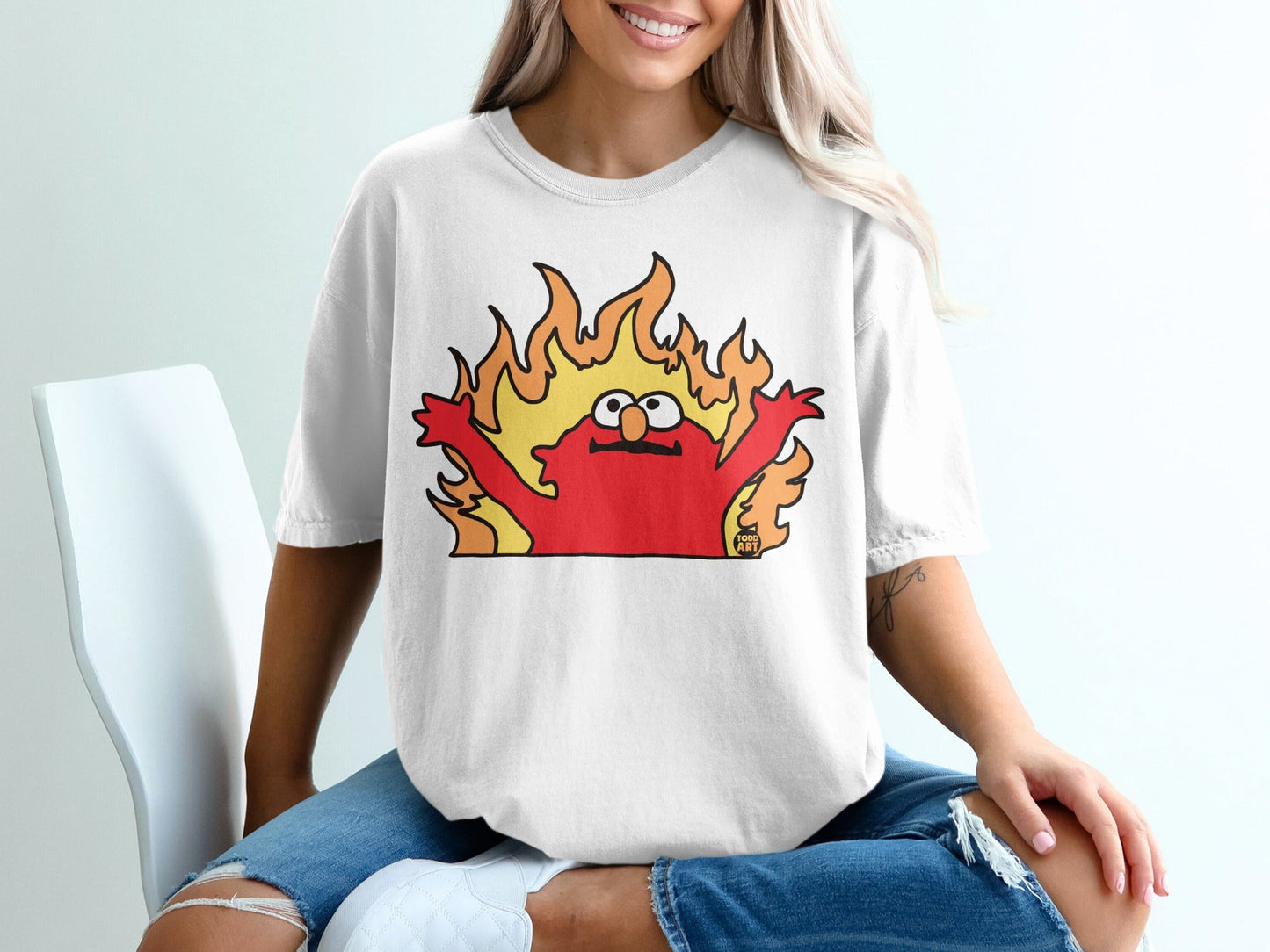 Cartoon Elmo character on a white t-shirt with flames behind him.
