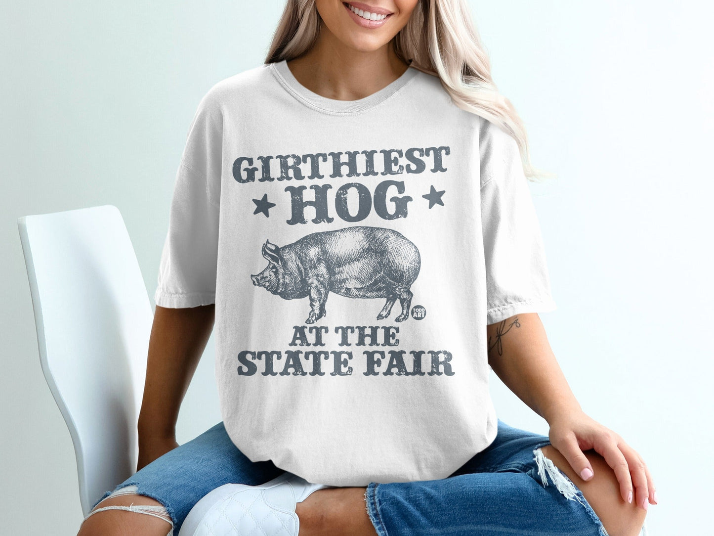 White t-shirt with "GIRTHIEST HOG AT THE STATE FAIR" text and pig graphic.