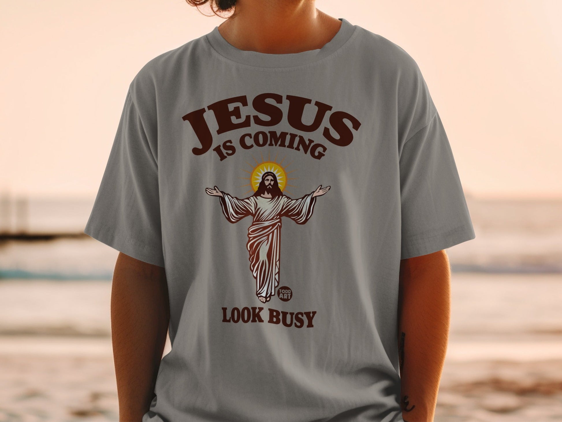 Jesus is coming look busy graphic on a grey t-shirt.