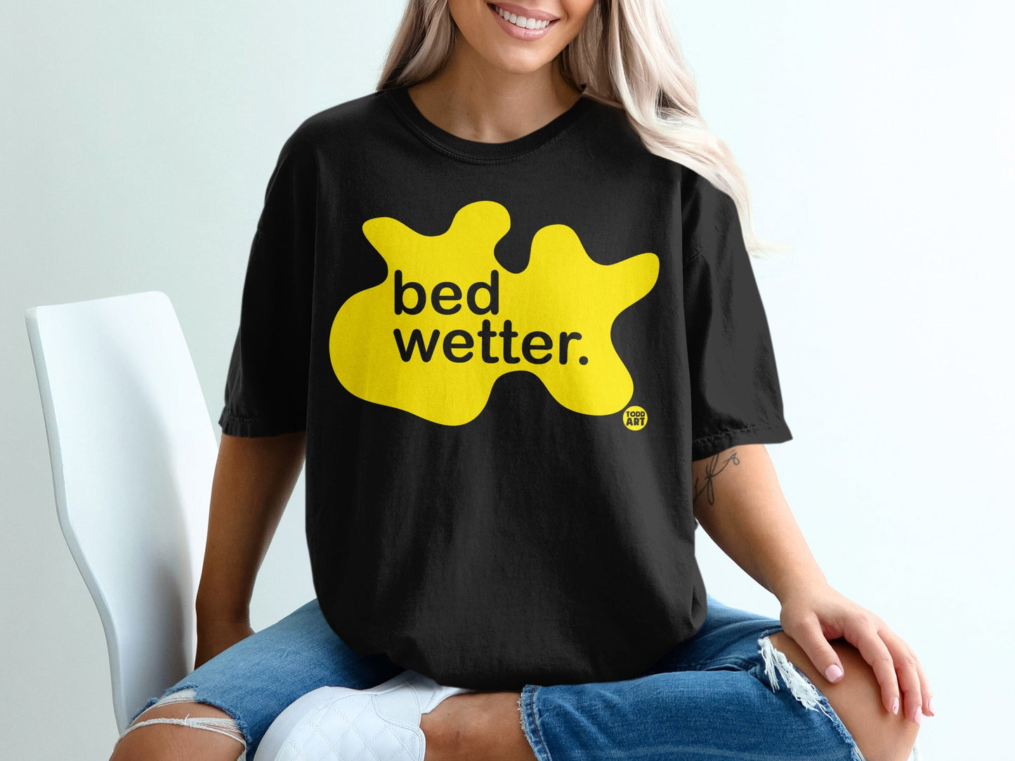 Black t-shirt with yellow "bed wetter." graphic and small "Good Art" logo.
