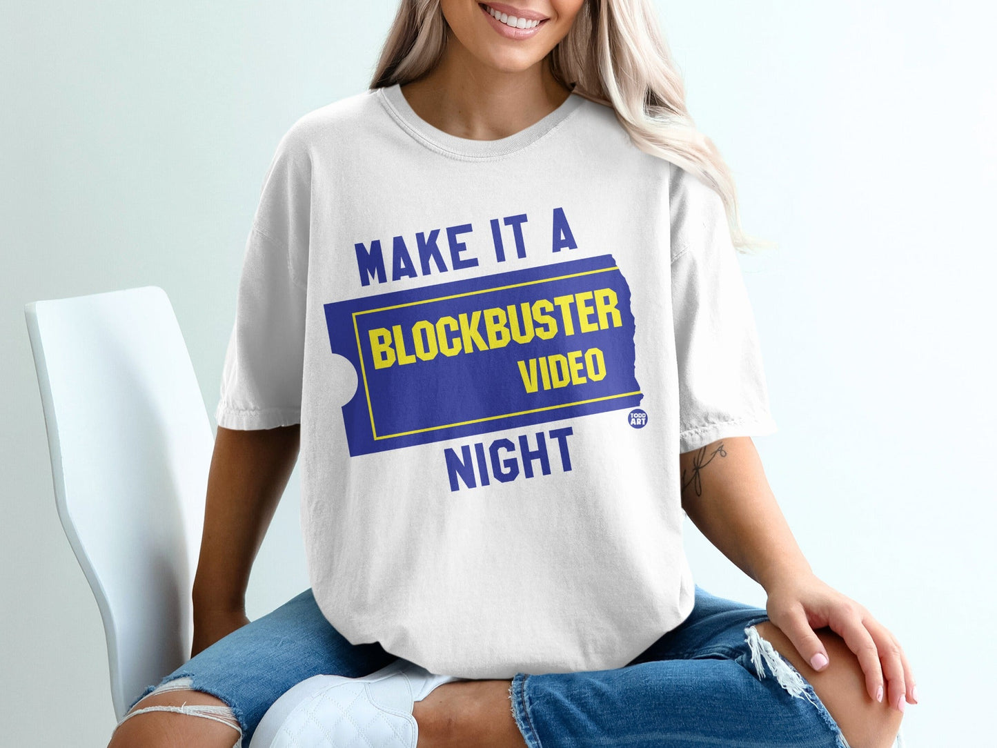 White t-shirt with "MAKE IT A BLOCKBUSTER NIGHT" in blue and yellow.