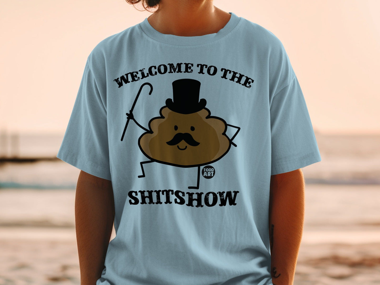 Light blue t-shirt with cartoon poop wearing top hat and holding cane, text "WELCOME TO THE SHITSHOW".