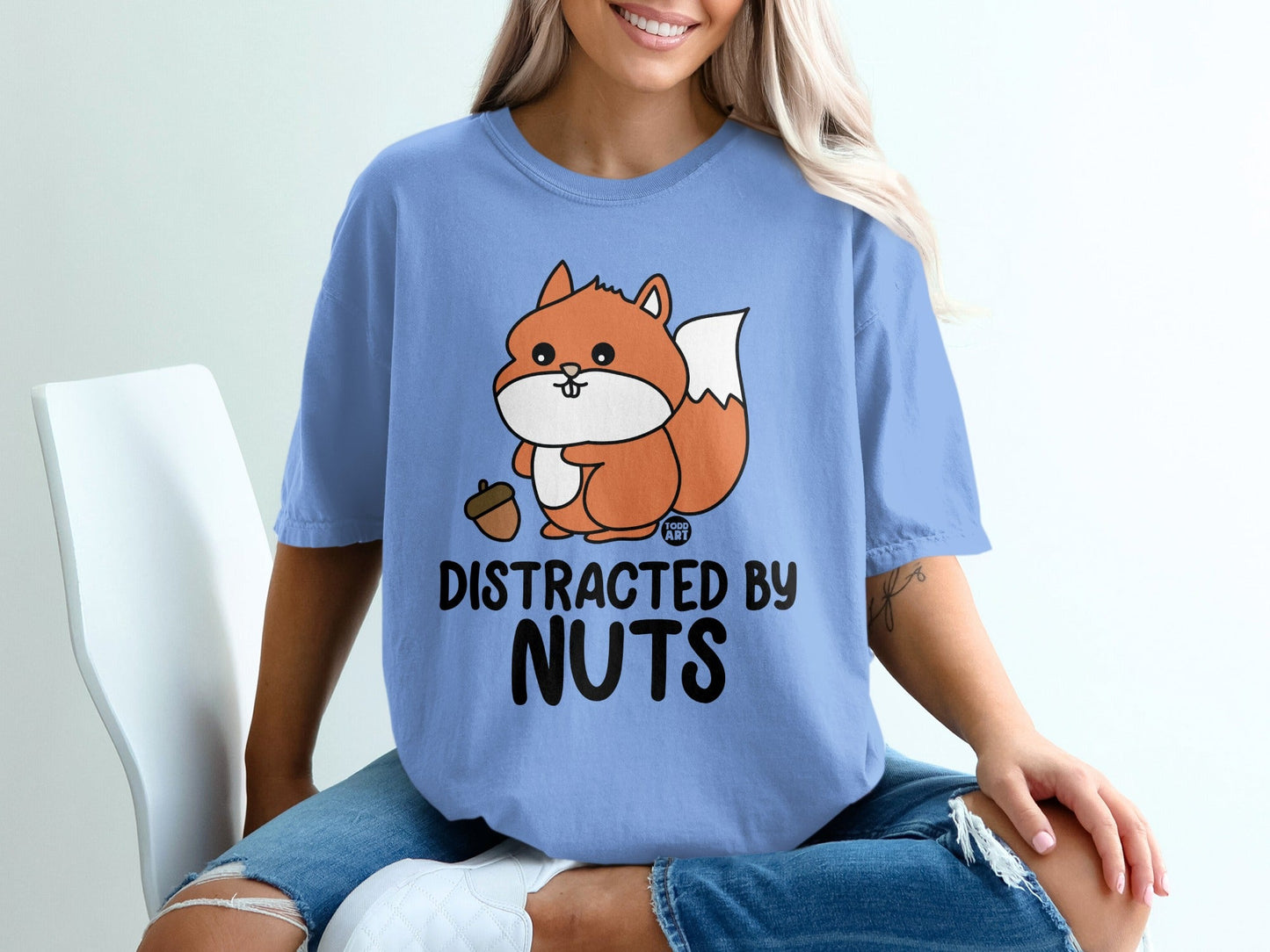 Blue t-shirt with a cartoon squirrel holding an acorn and the text "DISTRACTED BY NUTS".