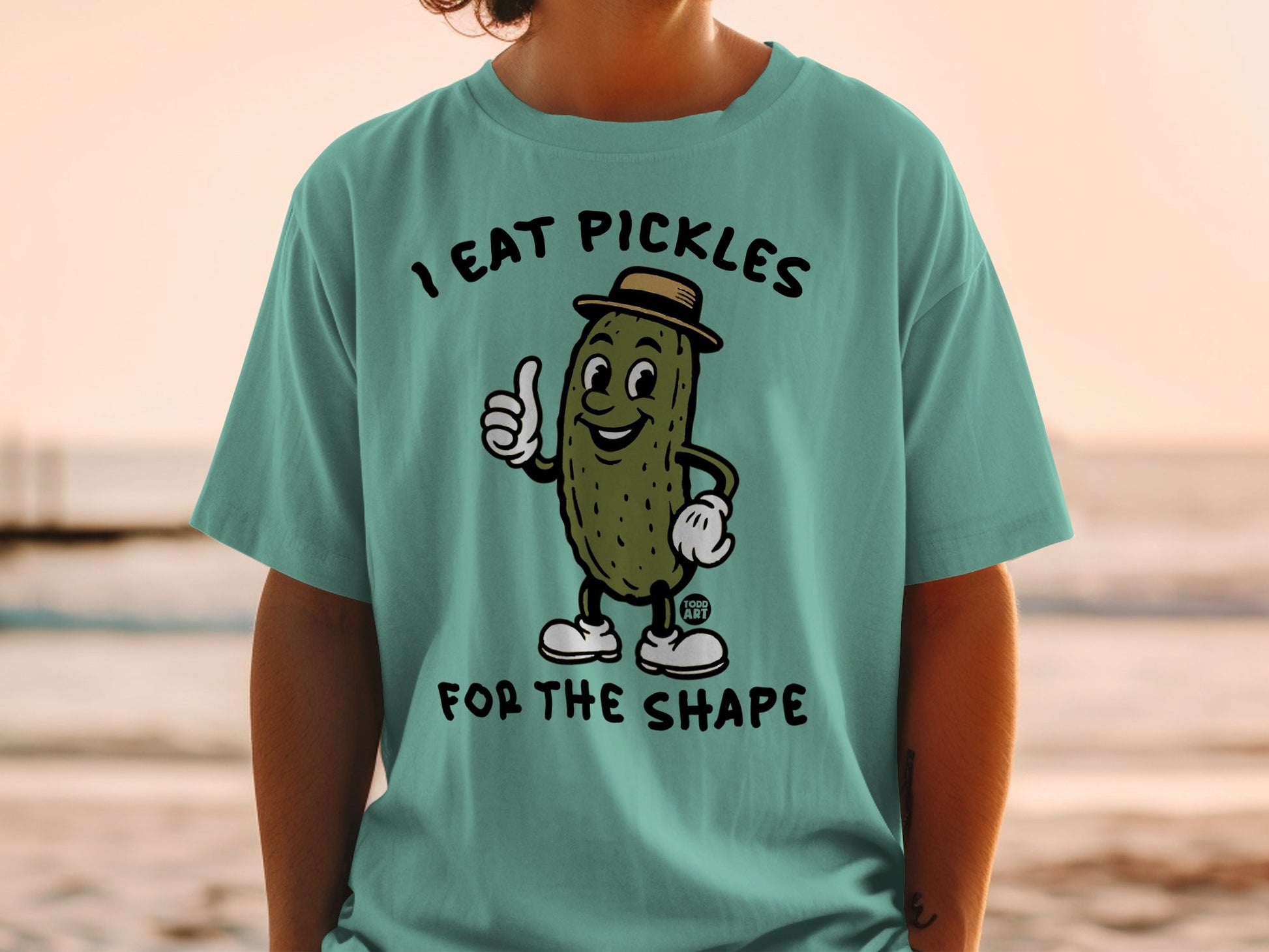 Cartoon pickle in a hat gives a thumbs up on a t-shirt.