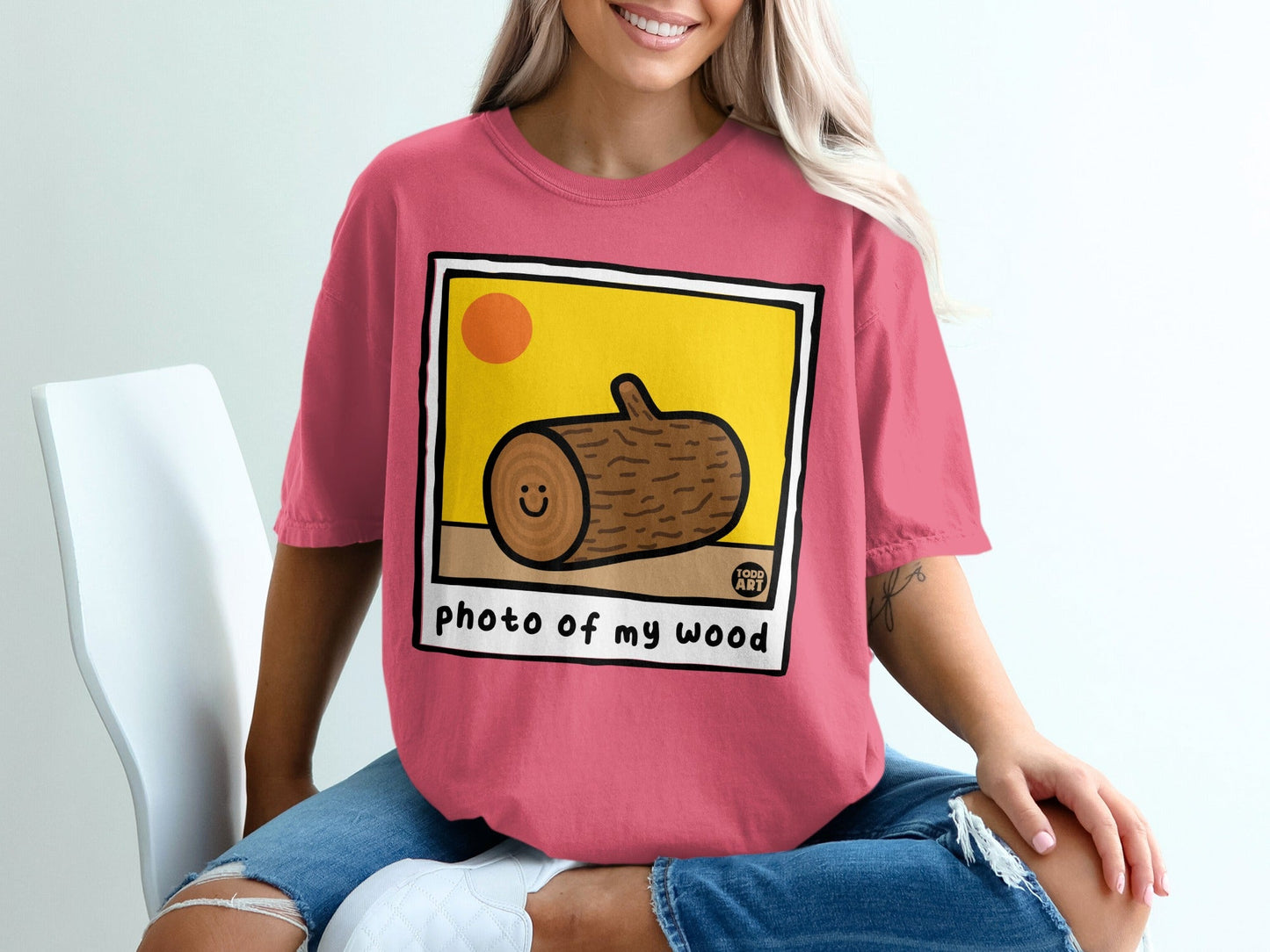 Pink t-shirt featuring a cartoon log with a smiley face and "photo of my wood" text.