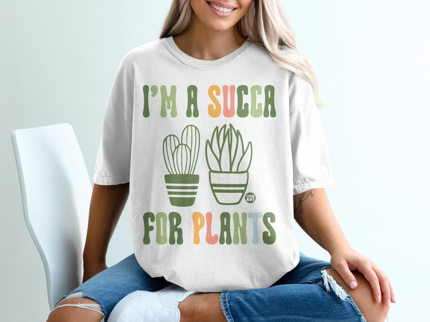 White t-shirt with green text "I'M A SUCCA FOR PLANTS" and potted succulents.