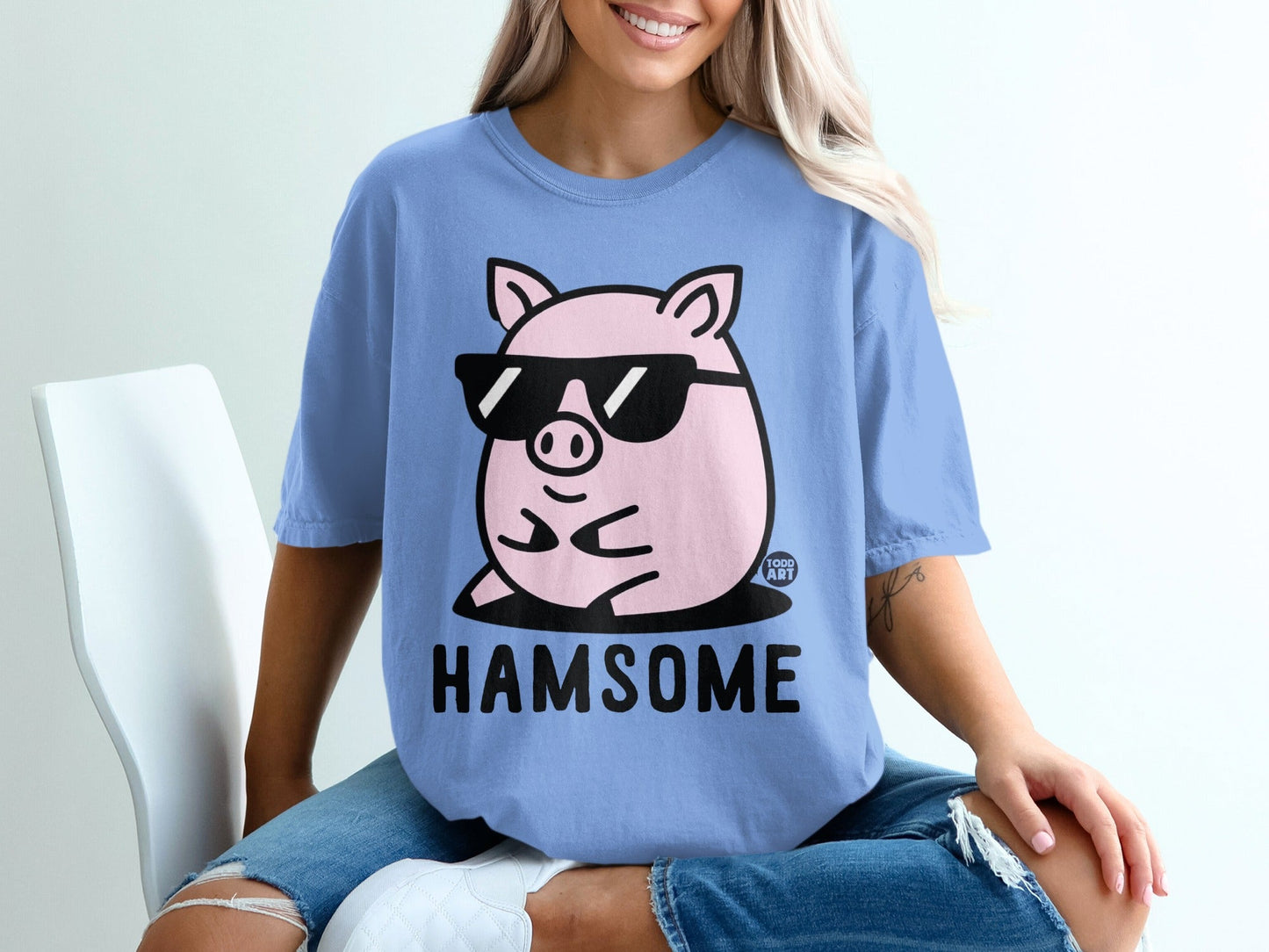 Blue t-shirt with a pink pig wearing sunglasses and the text "HAMSOME".