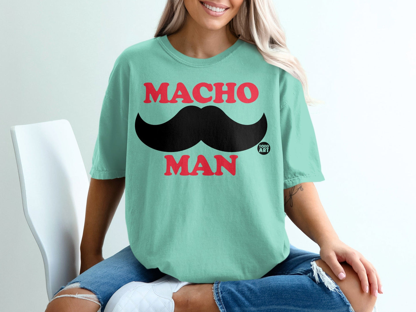 Teal t-shirt with red "MACHO MAN" text and a black mustache.
